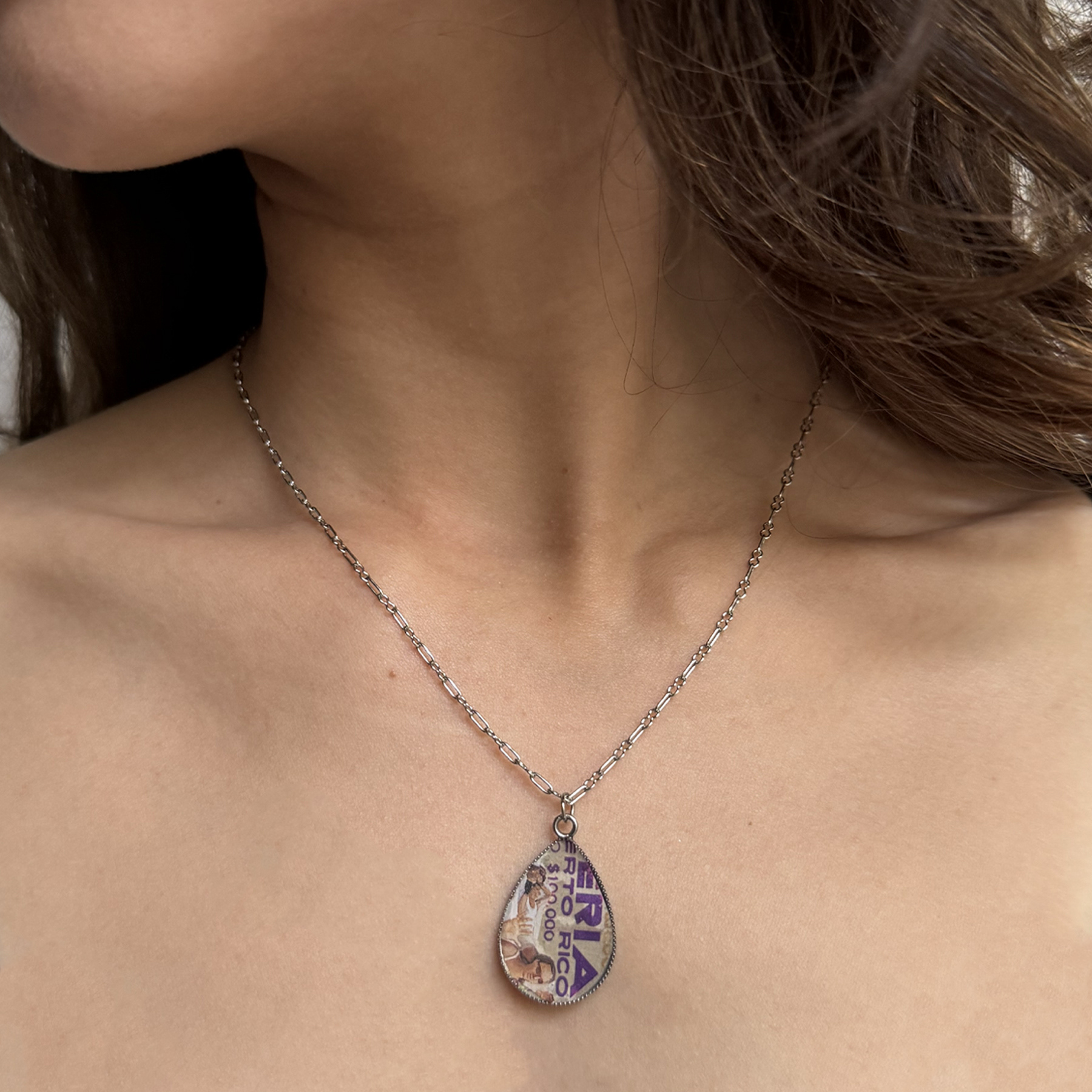 The necklace is made from a combination of a 1980 lottery ticket and a 2010 Communication Arts magazine, and it is set on stainless steel. A one-of-a-kind piece that blends nostalgia and modern design.