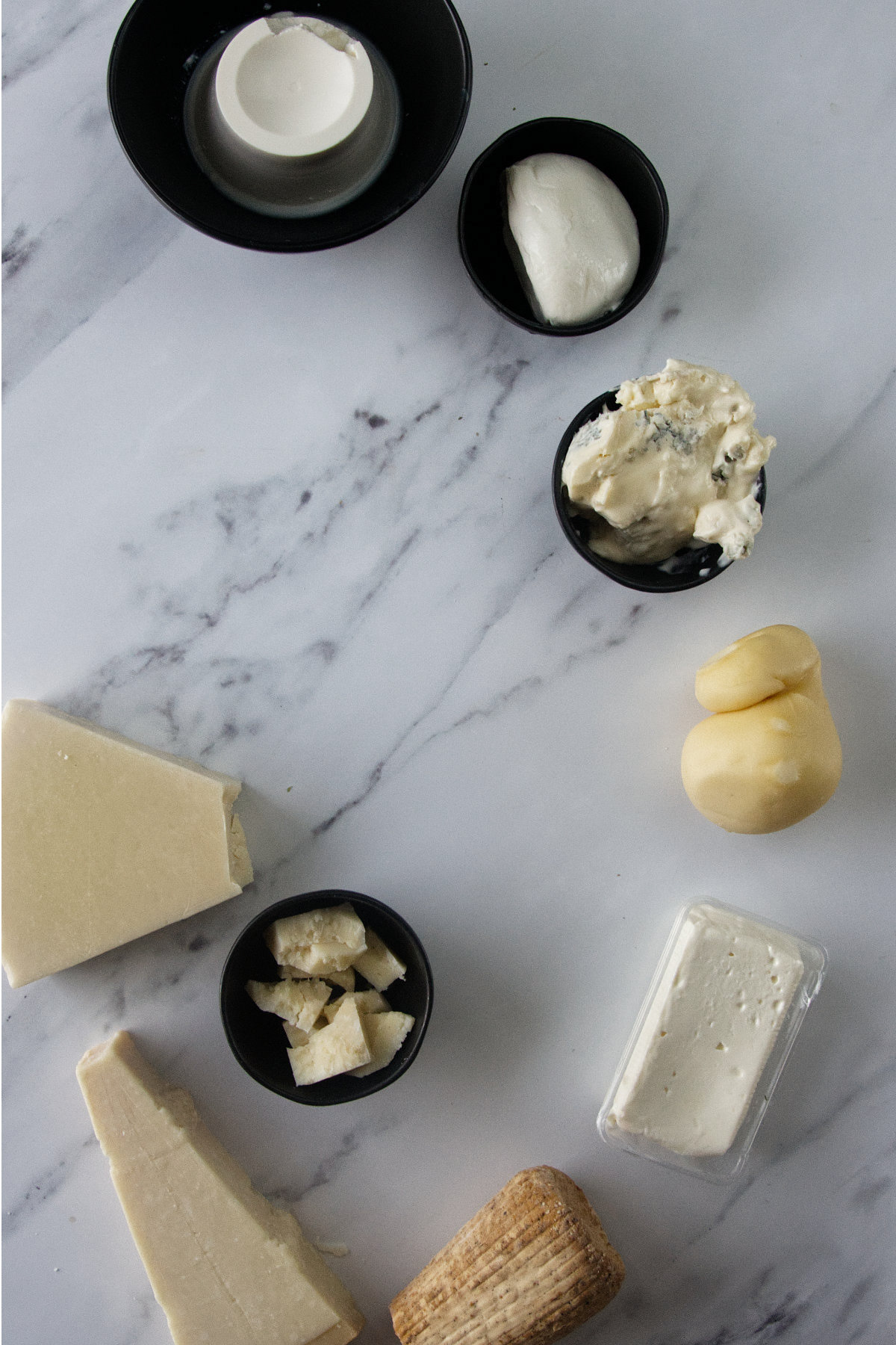 Selezione di Ricotta, Mozzarella, Gorgonzola, Scamorza, Stracchino, Pecorino e Parmigiano su marmo.