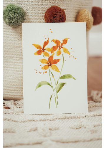 A photo of a small watercolor painting of three yellow flowers with stems and leaves in a loose and splashy style on a plain white background by artist Stephanie Fielden. It leans against home decor like a cheerful and inviting greeting card design.