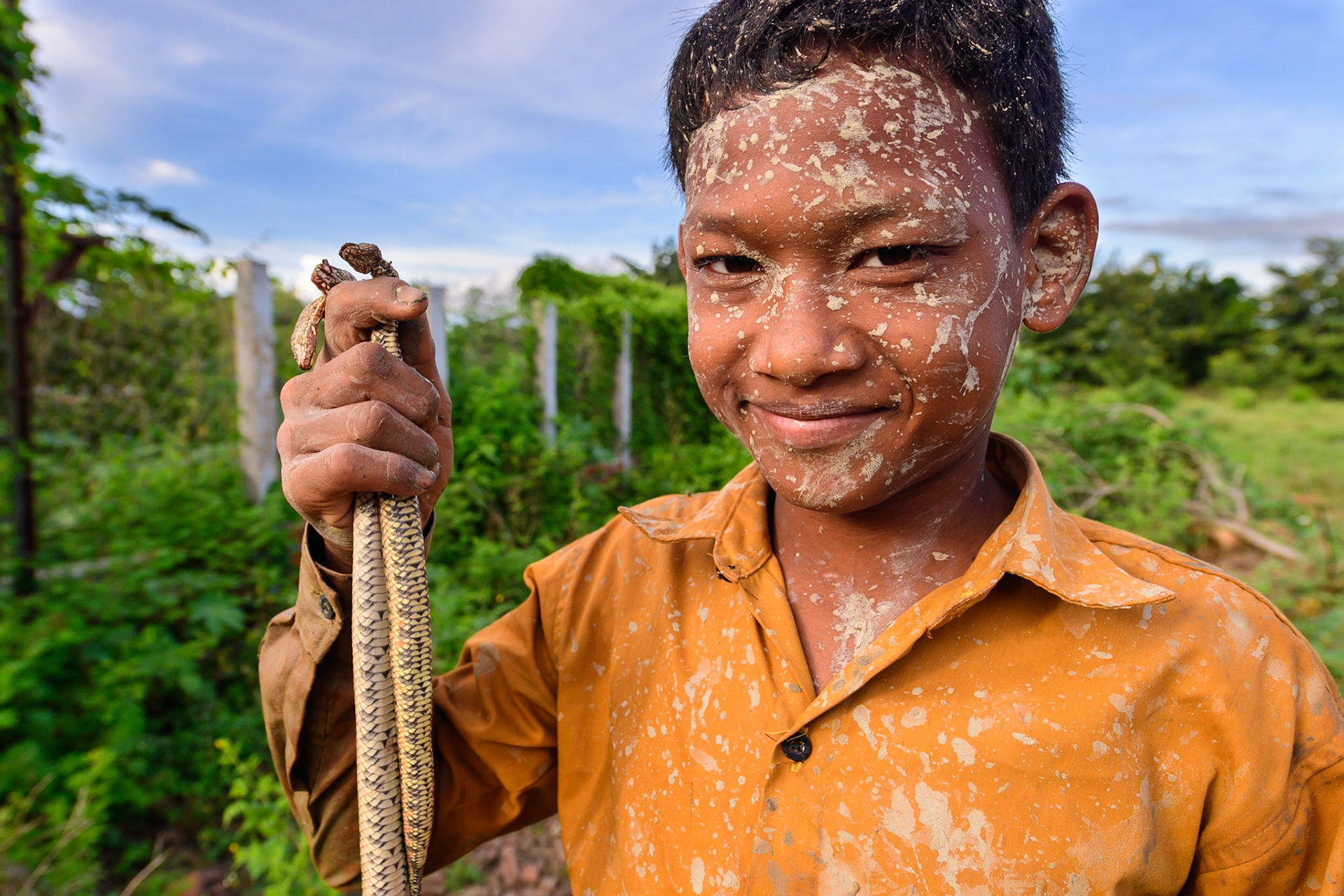 We were walking to a local family-owned brick factory in Battambang, Cambodia, where we bumped into a boy with mud on his face and snakes in his hands . He had been foraging in a local creek, looking for dinner. He was gracious enough to allow us some photos, for a buck.