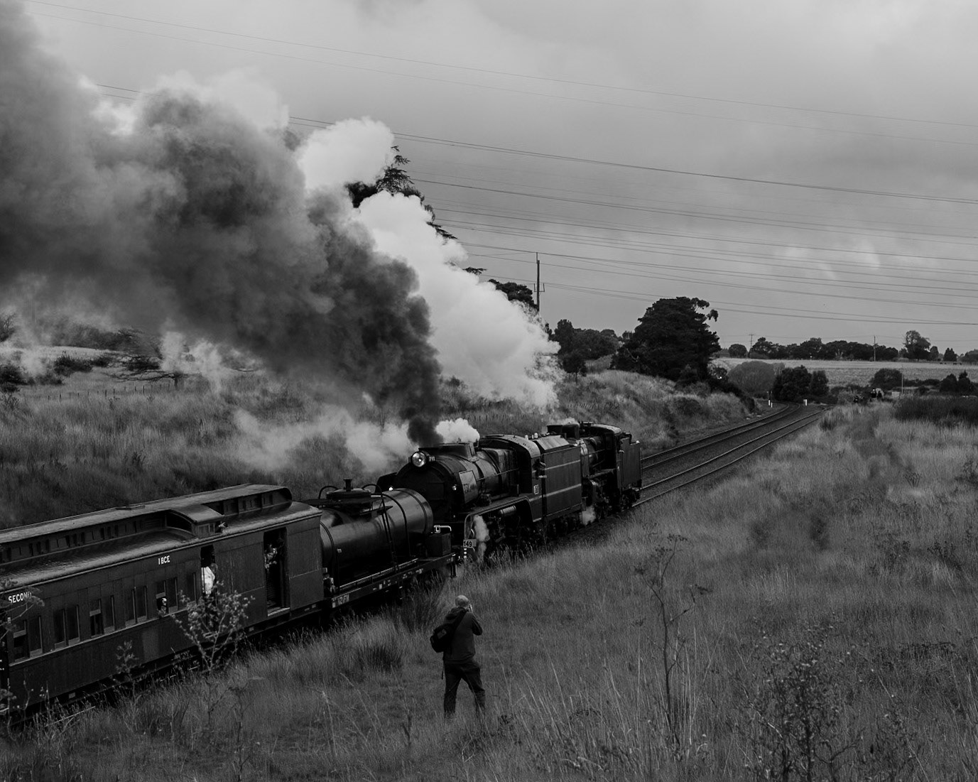 A lone photographer captures Steamrail's R711 and A2 986 powering up Warrenheip Bank. Ahead of the train, the two tracks split - on the left is the main line to Melbourne via Bacchus Marsh, and the right continues onwards to Geelong. Once a busy junction station with platforms, buildings, a signal box, and sidings, nowadays little remains to indicate this was once an important waypoint on the way to Victoria's goldfields.