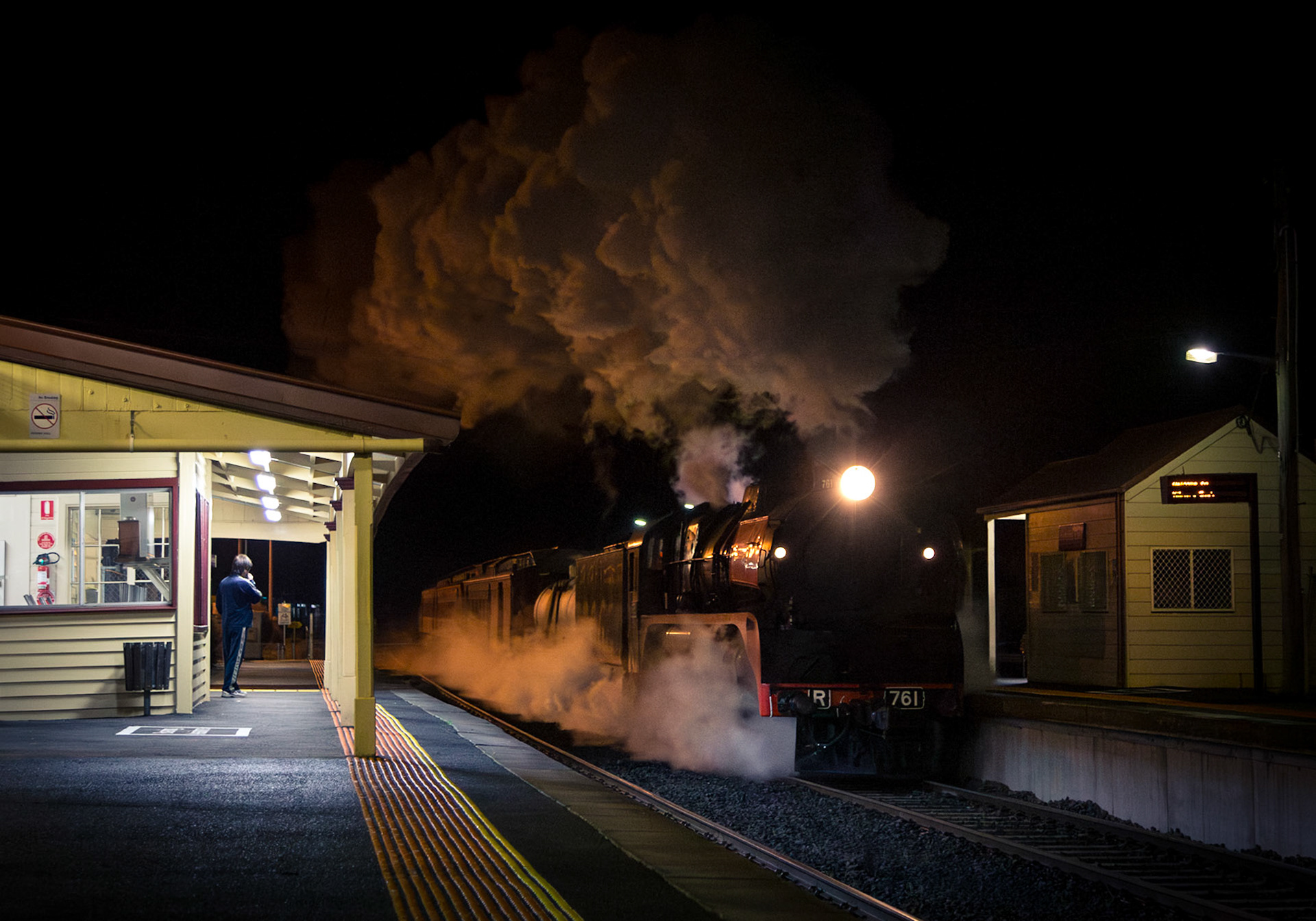 R761 roars through Kilmore East, its exhaust climbing high into the sky, as it returns to Melbourne with Steamrail's "Echuca Explorer". This train was to be held at Kilmore East on account of driver issues with an oncoming train, but as it neared the level crossing in the background the signal behind camera changed from stop to proceed, allowing R761's driver to open the throttle and take off into the night.