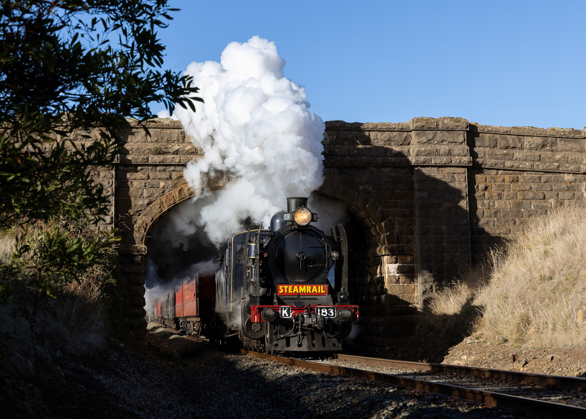 It's a mild autumn morning at Navigators as K183 erupts from underneath the bluestone road bridge. K183 and A2 986 were sequestered to Ballarat for the annual heritage weekend, providing shuttle trains from Ballarat to Yendon and return.