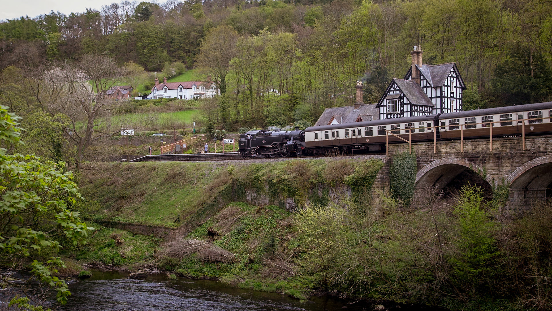 Ex-British Railways no. 80072 eases into the riverside station of Berwyn, on the Llangollen Railway in North Wales.Situated on the present day Llangollen Railway the station was opened in 1865 as part of the Llangollen and Corwen railway, which later formed part of the larger Ruabon-Barmouth railway. The station fell into disuse in December 1964, before the lines closure in January 1965. The famous Chain Bridge is just out-of-shot on the left.