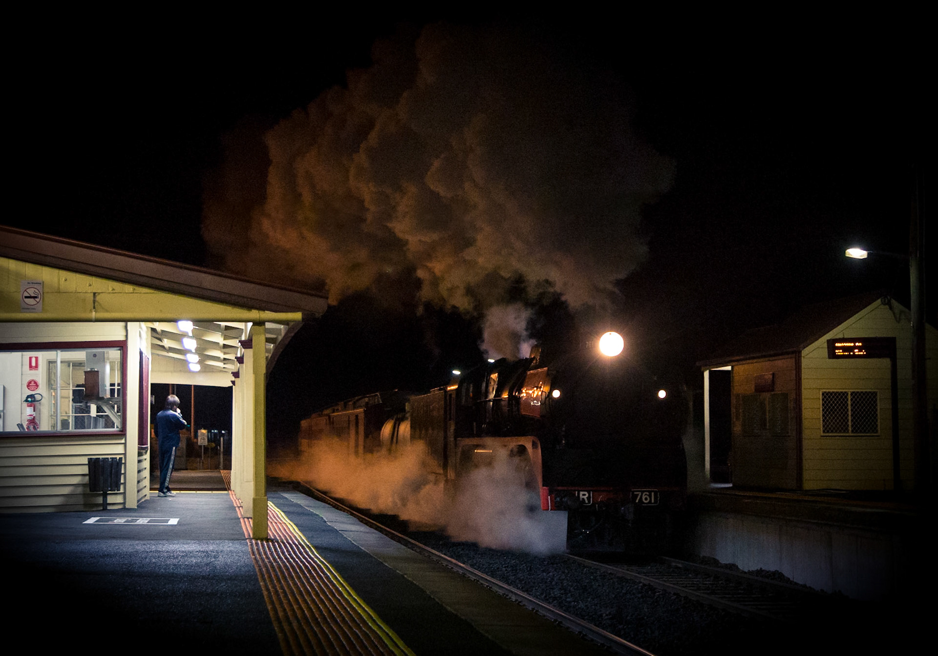 R761 roars through Kilmore East, its exhaust climbing high into the sky, as it returns to Melbourne with Steamrail's "Echuca Explorer". This train was to be held at Kilmore East on account of driver issues with an oncoming train, but as it neared the level crossing in the background the signal behind camera changed from stop to proceed, allowing R761's driver to open the throttle and take off into the night.