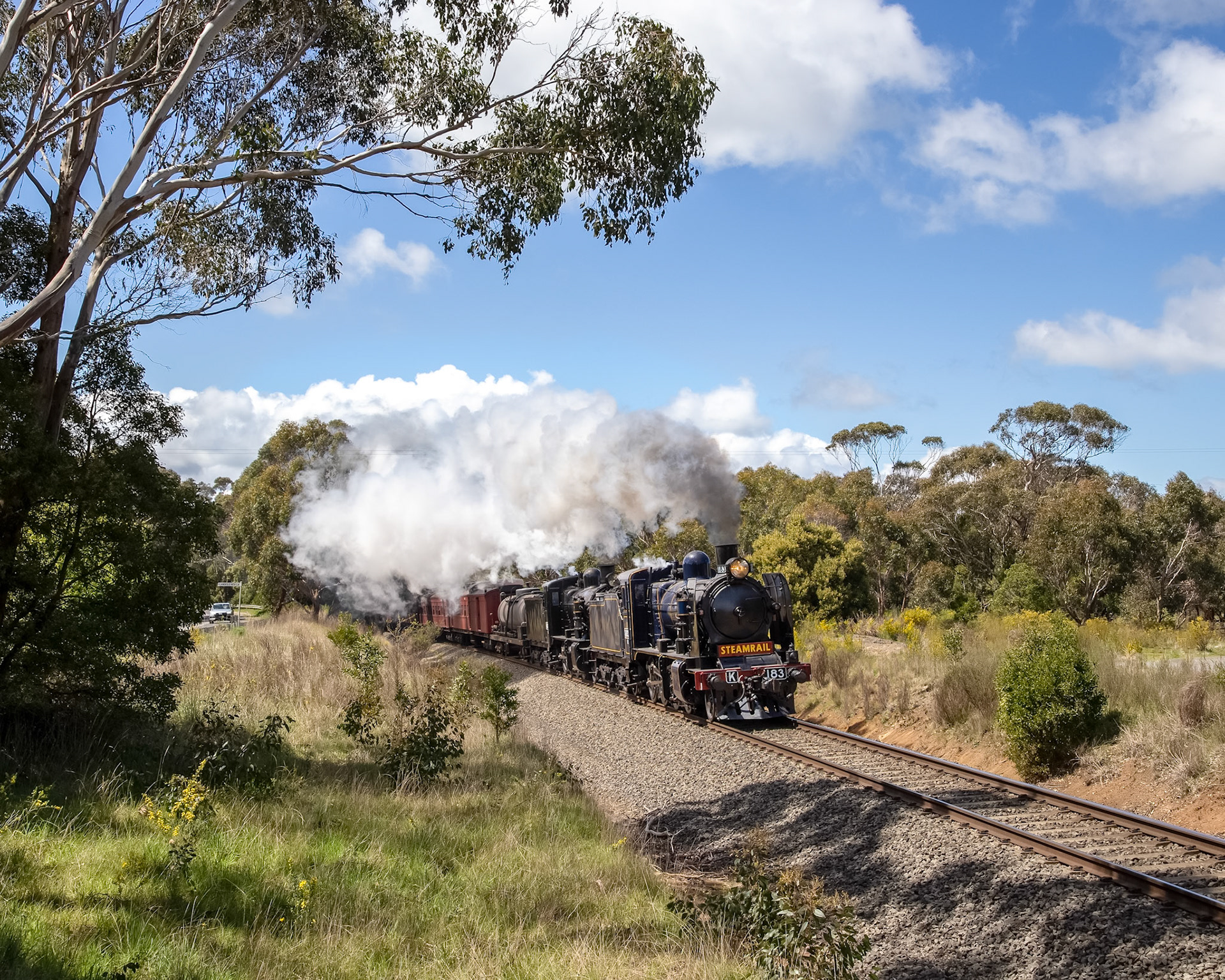 After stopping at Bostock Loop - on the outskirts of Ballan - for a watering stop, K class locos K183 and K153 (running as K100) roar uphill towards Ballarat. Originally intended to run as a triple-header with K190, due to a boiler defect T395 was substituted at the last minute and added to the end of the train for additional power for the climb through Bacchus Marsh.