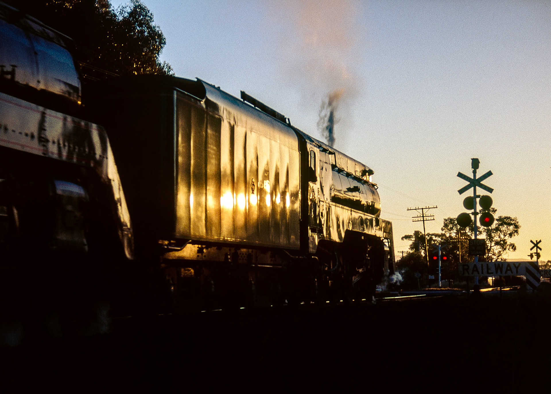 Departing Stawell for their overnight stop at Dimboola, 3801 and 3830 glow in the late evening sun as they cross the level crossing at Lake Road.