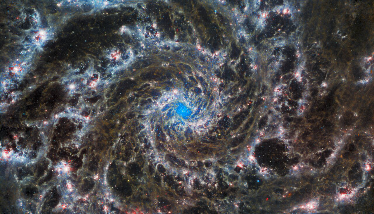 This image from the NASA/ESA/CSA James Webb Space Telescope shows the heart of M74, otherwise known as the Phantom Galaxy. Webb’s sharp vision has revealed delicate filaments of gas and dust in the grandiose spiral arms which wind outwards from the centre of this image. A lack of gas in the nuclear region also provides an unobscured view of the nuclear star cluster at the galaxy's centre. M74 is a particular class of spiral galaxy known as a ‘grand design spiral’, meaning that its spiral arms are prominent and well-defined, unlike the patchy and ragged structure seen in some spiral galaxies.  The Phantom Galaxy is around 32 million light-years away from Earth in the constellation Pisces, and lies almost face-on to Earth. This, coupled with its well-defined spiral arms, makes it a favourite target for astronomers studying the origin and structure of galactic spirals.  Webb gazed into M74 with its Mid-InfraRed Instrument (MIRI) in order to learn more about the earliest phases of star formation in the local Universe. These observations are part of a larger effort to chart 19 nearby star-forming galaxies in the infrared by the international PHANGS collaboration. Those galaxies have already been observed using the NASA/ESA Hubble Space Telescope and ground-based observatories. The addition of crystal-clear Webb observations at longer wavelengths will allow astronomers to pinpoint star-forming regions in the galaxies, accurately measure the masses and ages of star clusters, and gain insights into the nature of the small grains of dust drifting in interstellar space.  Hubble observations of M74 have revealed particularly bright areas of star formation known as HII regions. Hubble’s sharp vision at ultraviolet and visible wavelengths complements Webb’s unparalleled sensitivity at infrared wavelengths, as do observations from ground-based radio telescopes such as the Atacama Large Millimeter/submillimeter Array, ALMA. By combining data from telescopes operating across the electromagnetic spectrum, scientists can gain greater insight into astronomical objects than by using a single observatory — even one as powerful as Webb!  MIRI was contributed by ESA and NASA, with the instrument designed and built by a consortium of nationally funded European Institutes (the MIRI European Consortium) in partnership with JPL and the University of Arizona.  Credit: ESA/Webb, NASA & CSA, J. Lee and the PHANGS-JWST Team.  Acknowledgement: J. Schmidt