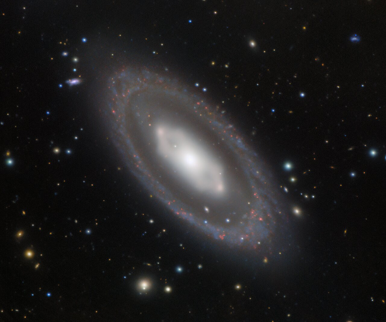 NGC 7020, a barred lenticular galaxy in the southern constellation Pavo, holds a geometric mystery. Clear but subtle in this image from Gemini South, one half of the International Gemini Observatory, a Program of NSF’s NOIRLab, the core of NGC 7020 is visibly hexagonal in shape. A hexagon is not a common shape for any celestial body, let alone an entire galaxy. To form a hexagonal structure such as this, a considerable number of stars must orbit in a very narrow band. This orbital path includes two denser regions of stars seen on the left and right sides of the hexagon, which are known as “ansae”. NGC 7020’s unusual shape seems to be the product of a very rare orbital resonance, or an as-yet-unknown phenomenon.   The 8-meter Gemini South telescope is located on Cerro Pachón in the Chilean Andes. Along with the other half of the international Gemini observatory, Gemini North in Hawai‘i, these two telescopes give us a deep view of the entire night sky.  Credit: International Gemini Observatory/NOIRLab/NSF/AURA/H. Dottori, R. J. Díaz, G. Gimeno  Image processing: T.A. Rector (University of Alaska Anchorage/NSF’s NOIRLab), M. Zamani (NSF’s NOIRLab) & D. de Martin (NSF’s NOIRLab)