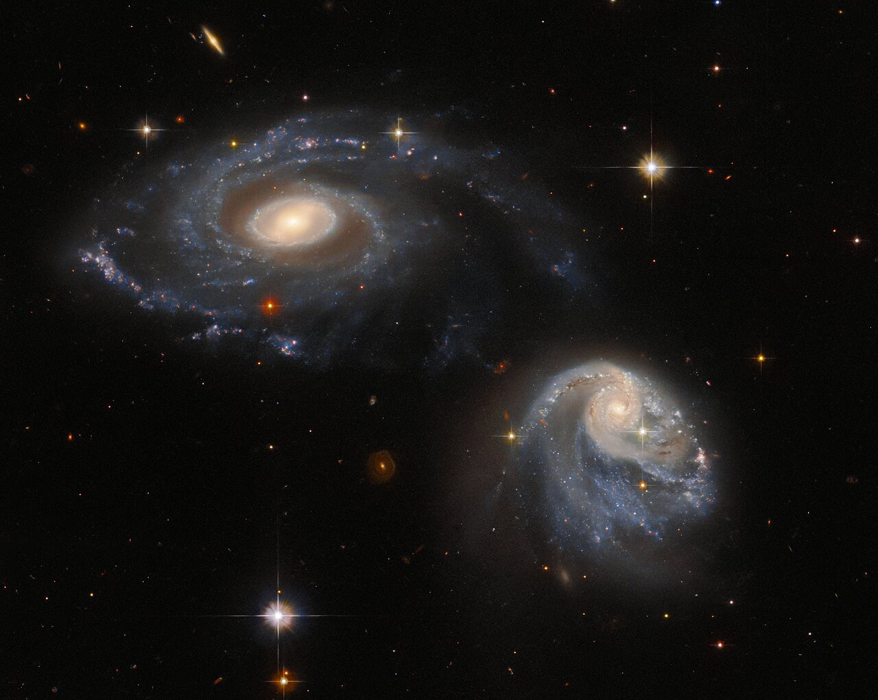 The two interacting galaxies making up the pair known as Arp-Madore 608-333 seem to float side by side in this image from the NASA/ESA Hubble Space Telescope. Though they appear serene and unperturbed, the two are subtly warping one another through a mutual gravitational interaction that is disrupting and distorting both galaxies. This drawn-out galactic interaction was captured by Hubble’s Advanced Camera for Surveys.  The interacting galaxies in Arp-Madore 608-333 were captured as part of an effort to build up an archive of interesting targets for more detailed future study with Hubble, ground-based telescopes, and the NASA/ESA/CSA James Webb Space Telescope. To build up this archive, astronomers scoured existing astronomical catalogues for a list of targets spread throughout the night sky. By so doing, they hoped to include objects that had already been identified as interesting and that would be easy for Hubble to observe no matter which direction it was pointing.  Deciding how to award Hubble observing time is a drawn-out, competitive and difficult process, and the observations are allocated so as to use every last second of Hubble time available. However, there is a small but persistent fraction of time — around 2–3% — that goes unused as Hubble turns to point at new targets. Snapshot programmes, such as the one which captured Arp-Madore 608-333, exist to fill this gap and take advantage of the moments between longer observations. As well as creating beautiful images such as this, these snapshot programs enable astronomers to gather as much data as possible with Hubble.  Links Video of A Snapshot of Interacting Galaxies Credit: ESA/Hubble & NASA, Dark Energy Survey/DOE/FNAL/DECam/CTIO/NOIRLab/NSF/AURA, J. Dalcanton
