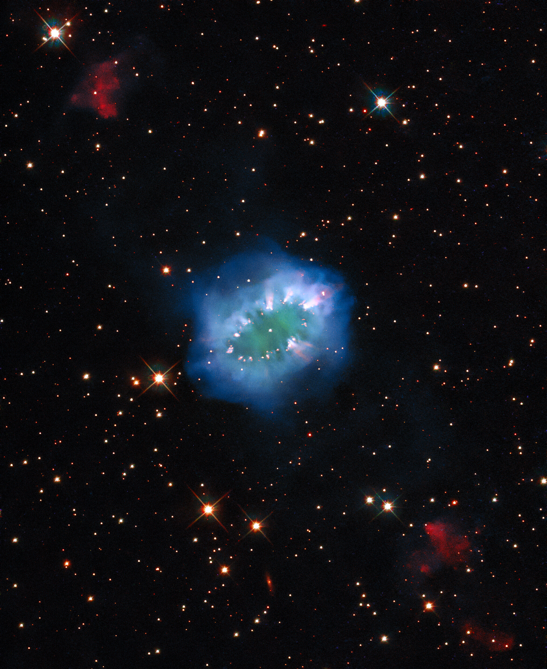 The interaction of two doomed stars has created this spectacular ring adorned with bright clumps of gas — a diamond necklace of cosmic proportions. Fittingly known as the Necklace Nebula, this planetary nebula is located 15 000 light-years away from Earth in the small, dim constellation of Sagitta (The Arrow).  The Necklace Nebula — which also goes by the less glamorous name of PN G054.2-03.4 — was produced by a pair of tightly orbiting Sun-like stars. Roughly 10 000 years ago, one of the aging stars expanded and engulfed its smaller companion, creating something astronomers call a “common envelope”. The smaller star continued to orbit inside its larger companion, increasing the bloated giant’s rotation rate until large parts of it spun outwards into space. This escaping ring of debris formed the Necklace Nebula, with particularly dense clumps of gas forming the bright “diamonds” around the ring.  The pair of stars which created the Necklace Nebula remain so close together — separated by only a few million kilometres — that they appear as a single bright dot in the centre of this image. Despite their close encounter the stars are still furiously whirling around each other, completing an orbit in just over a day.   The Necklace Nebula was featured in a previously released Hubble image, but now this new image has been created by applying advanced processing techniques, making for a new and improved view of this intriguing object. The composite image includes several exposures from Hubble’s Wide Field Camera 3.  Credit: ESA/Hubble & NASA, K. Noll