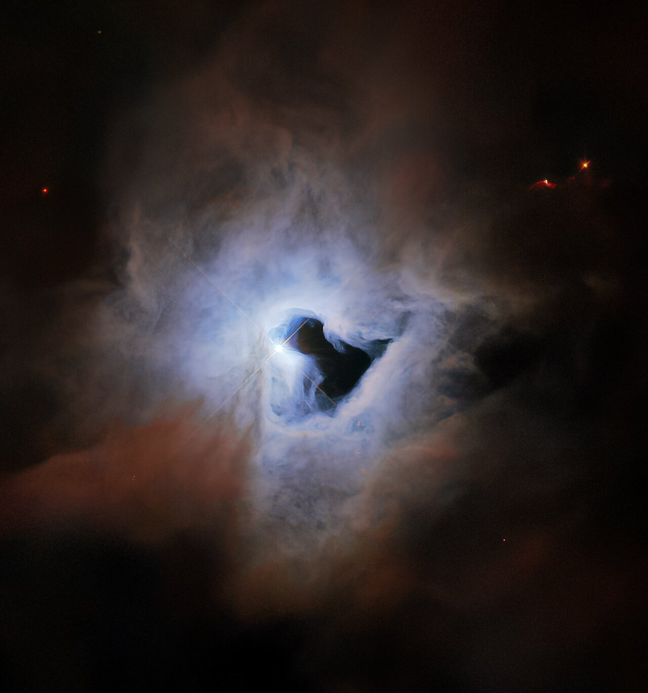 This peculiar portrait from the NASA/ESA Hubble Space Telescope showcases NGC 1999, a reflection nebula in the constellation Orion. NGC 1999 is around 1350 light-years from Earth and lies near to the Orion Nebula, the closest region of massive star formation to Earth. NGC 1999 itself is a relic of recent star formation — it is composed of detritus left over from the formation of a newborn star.  Just like fog curling around a street lamp, reflection nebulae like NGC 1999 only shine because of the light from an embedded source. In the case of NGC 1999, this source is the aforementioned newborn star V380 Orionis which is visible at the centre of this image. The most notable aspect of NGC 1999’s appearance, however, is the conspicuous hole in its centre, which resembles an inky-black keyhole of cosmic proportions.  This image was created from archival Wide Field Planetary Camera 2 observations that date from shortly after Servicing Mission 3A in 1999. At the time, astronomers believed that the dark patch in NGC 1999 was something called a Bok globule — a dense, cold cloud of gas, molecules, and cosmic dust that blots out background light. However, follow-up observations using a collection of telescopes including ESA’s Herschel Space Observatory revealed that the dark patch is actually an empty region of space. The origin of this unexplained rift in the heart of NGC 1999 remains unknown.  Links Video of Cosmic Keyhole Credit: ESA/Hubble & NASA, ESO, K. Noll