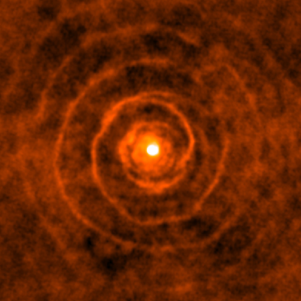 Celestial spiral with a twist Although it looks like the pattern of a shell on the beach, this intriguing spiral is in fact astronomical in nature. The Atacama Large Millimeter/submillimeter Array (ALMA) captured this remarkable image of a binary star system, where two stars — LL Pegasi and its companion — are locked in a stellar waltz, orbiting around their common centre of gravity. The old star LL Pegasi is continuously losing gaseous material as it evolves into a planetary nebula, and the distinct spiral shape is the imprint made by the stars orbiting in this gas.  The spiral spans light-years and winds around with extraordinary regularity. Based on the expansion rate of the spiralling gas, astronomers estimate that a new “layer” appears every 800 years — approximately the same time it takes for the two stars to complete one orbit around each other.  LL Pegasi was first highlighted about 10 years ago when the NASA/ESA Hubble Space Telescope obtained a picture of the almost-perfect spiral structure. This was the first time a spiral pattern had been found in material surrounding an old star. Now, ALMA’s observations, of which this image only shows one “cross-section”, have added an extra dimension to reveal the exquisitely-ordered 3D geometry of the spiral pattern. A full view of the 3D video can be seen in this video. Credit: ALMA (ESO/NAOJ/NRAO)/H. Kim et al.