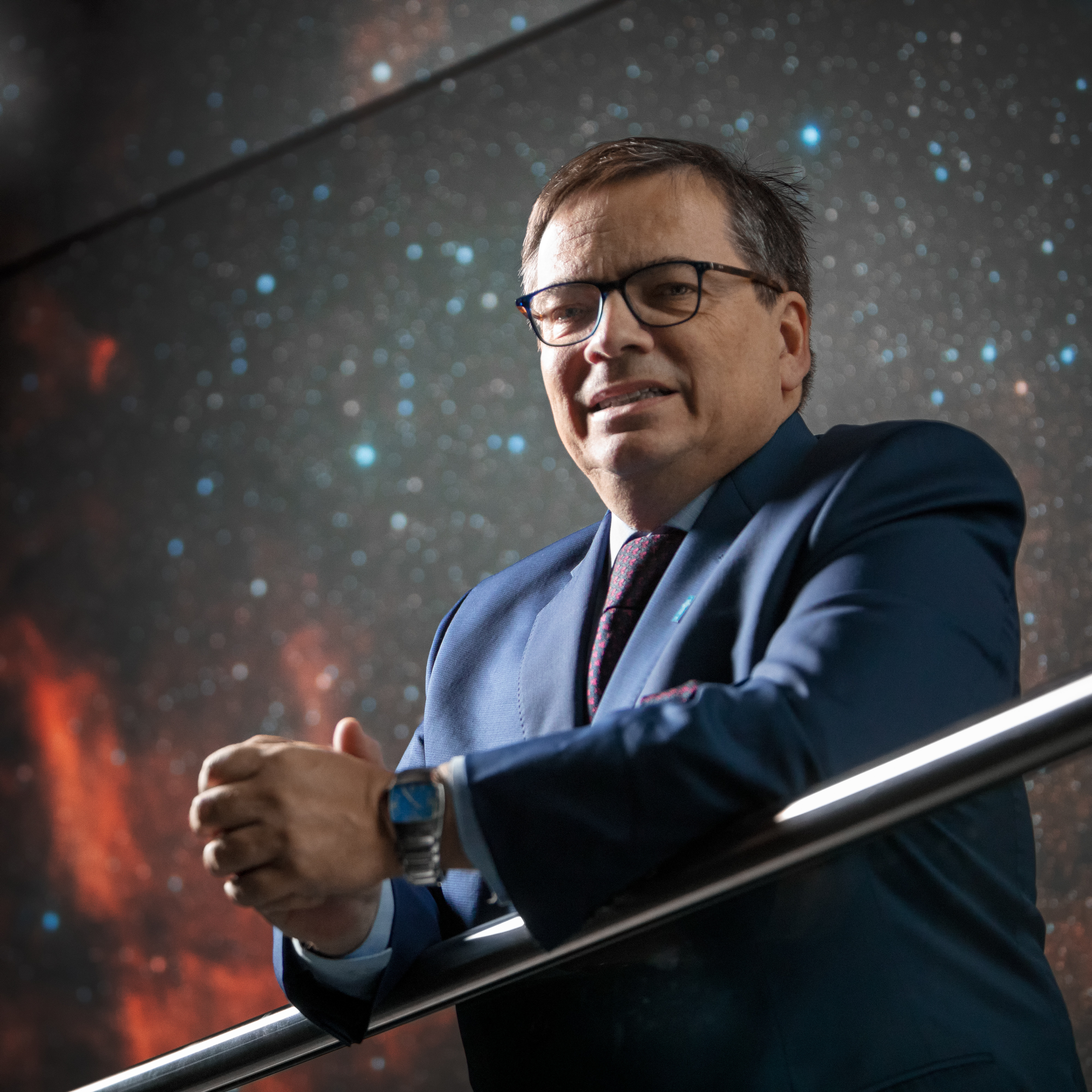 ESO Director General Xavier Barcons, standing in front of a panel depicting the Cygnus Nebula inside of the ESO Supernova Planetarium & Visitor Centre.