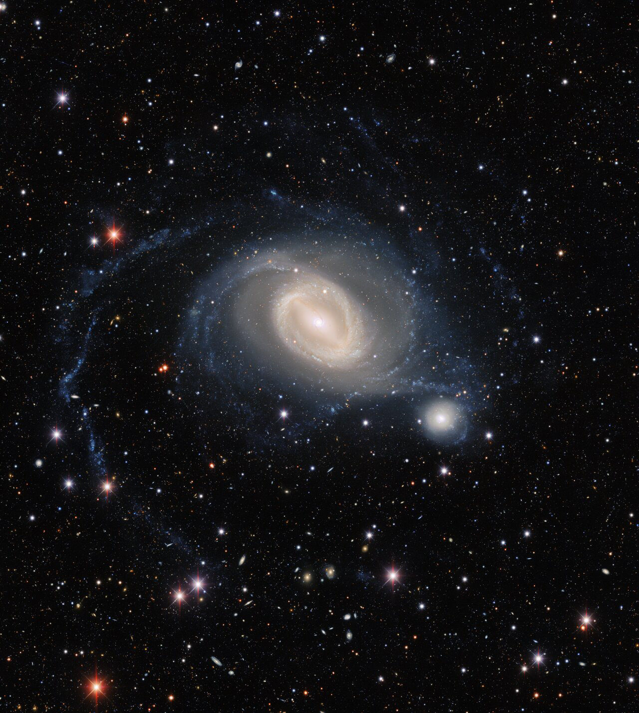 The interacting galaxy pair NGC 1512 and NGC 1510 take center stage in this image from the Dark Energy Camera, a state-of-the art wide-field imager on the Víctor M. Blanco 4-meter Telescope at Cerro Tololo Inter-American Observatory, a Program of NSF’s NOIRLab. NGC 1512 has been in the process of merging with its smaller galactic neighbor for 400 million years, and this drawn-out interaction has ignited waves of star formation and warped both galaxies.  Credit: Dark Energy Survey/DOE/FNAL/DECam/CTIO/NOIRLab/NSF/AURA Image processing: T.A. Rector (University of Alaska Anchorage/NSF’s NOIRLab), J. Miller (Gemini Observatory/NSF’s NOIRLab), M. Zamani & D. de Martin (NSF’s NOIRLab)