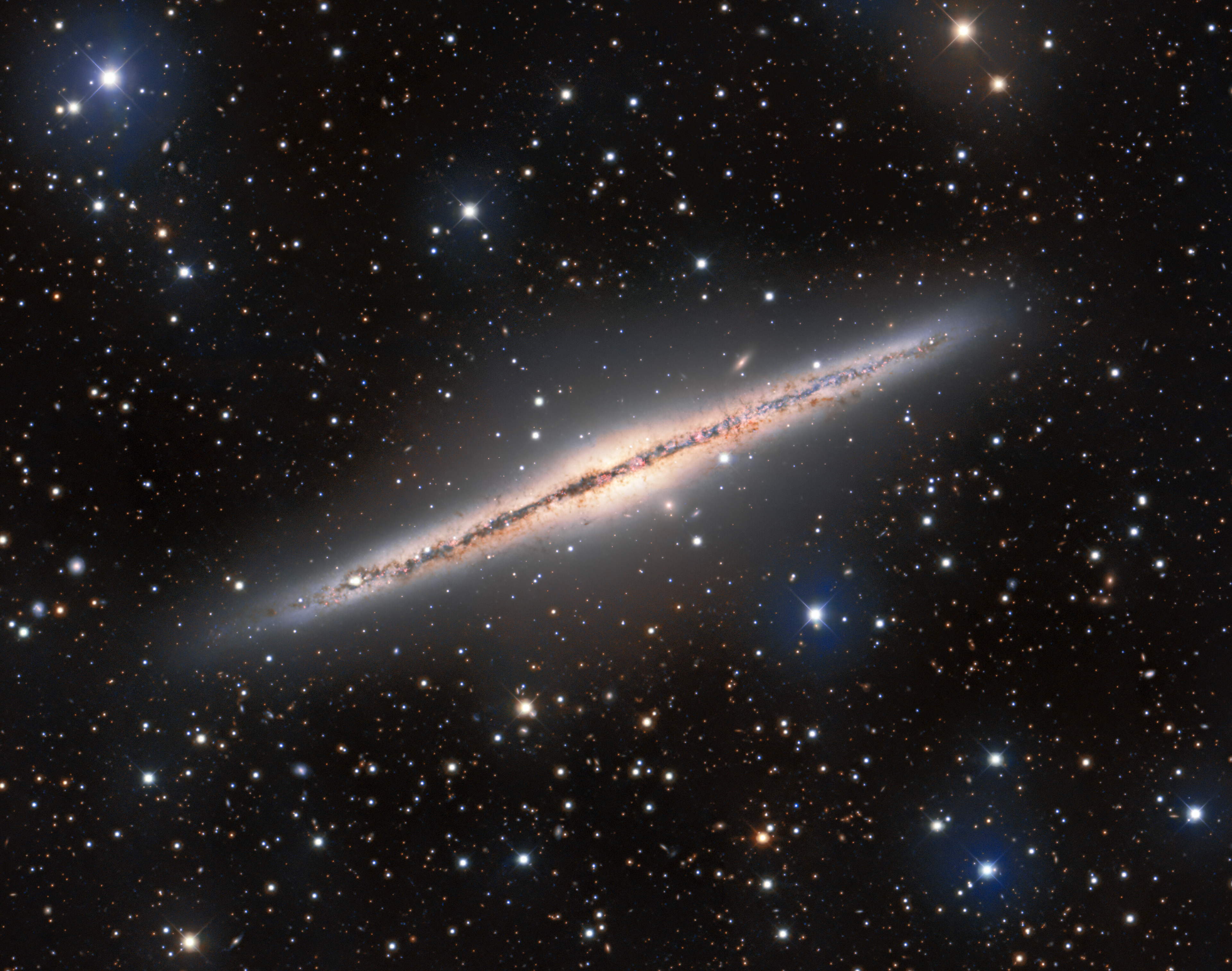 The Silver Sliver Galaxy — more formally known as NGC 891 — is shown in this striking image from the Mosaic instrument on the 4-meter Nicholas U. Mayall Telescope at Kitt Peak National Observatory, a Program of NSF’s NOIRLab. NGC 891 is a spiral galaxy that lies almost perfectly edge-on to us, leading to its elongated appearance and its striking resemblance to our home galaxy, the Milky Way, as seen from the Earth. Since NGC 891 is oriented edge-on, it’s great for investigating the galactic fountain model. When stellar winds and supernovae from the disk of a galaxy eject gas into the surrounding medium, it can create condensation that rains back down onto the disk. The condensed gas then provides new fuel for star formation. In addition to the portrait of NGC 891, this image is littered with astronomical objects near and far — bright foreground stars from our own galaxy intrude upon the view of NGC 891 and distant galaxies lurk in the background.  Credit: KPNO/NOIRLab/NSF/AURA Acknowledgements: PI: M T. Patterson (New Mexico State University) Image processing: Travis Rector (University of Alaska Anchorage), Mahdi Zamani & Davide de Martin
