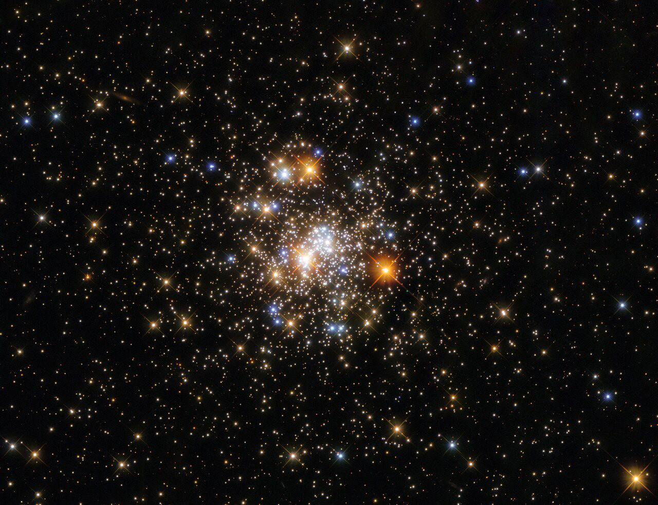 This star-studded image from the NASA/ESA Hubble Space Telescope depicts NGC 6717, which lies more than 20 000 light-years from Earth in the constellation Sagittarius. NGC 6717 is a globular cluster, a roughly spherical collection of stars tightly bound together by gravity. Globular clusters contain more stars in their centres than their outer fringes, as this image aptly demonstrates; the sparsely populated edges of NGC 6717 are in stark contrast to the sparkling collection of stars at its centre.  The centre of the image also contains some interlopers from closer to home. Bright foreground stars close to Earth are surrounded by criss-cross diffraction spikes formed by starlight interacting with the structures supporting Hubble’s secondary mirror.  The area of the night sky which contains the constellation Sagittarius also contains the centre of the Milky Way, which is filled with light-absorbing gas and dust. This absorption of light — which astronomers refer to as extinction — makes studying globular clusters near the Galactic centre a challenging endeavour. To determine the properties of NGC 6717, astronomers relied on a combination of Hubble’s Wide Field Camera 3 and the Advanced Camera for Surveys.  Links Video of A Glittering Globular Cluster Credit: ESA/Hubble and NASA, A. Sarajedini 