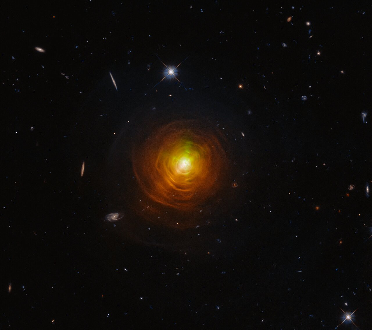 The NASA/ESA Hubble Space Telescope celebrates Halloween this year with a striking observation of the carbon star CW Leonis, which resembles a baleful orange eye glaring from behind a shroud of smoke.  CW Leonis glowers from deep within a thick shroud of dust in this image from the NASA/ESA Hubble Space Telescope. Lying roughly 400 light-years from Earth in the constellation Leo, CW Leonis is a carbon star — a luminous type of red giant star with a carbon-rich atmosphere. The dense clouds of sooty gas and dust engulfing this dying star were created as the outer layers of CW Leonis itself were thrown out into the void.  Credit: ESA/Hubble & NASA, T. Ueta, H. Kim