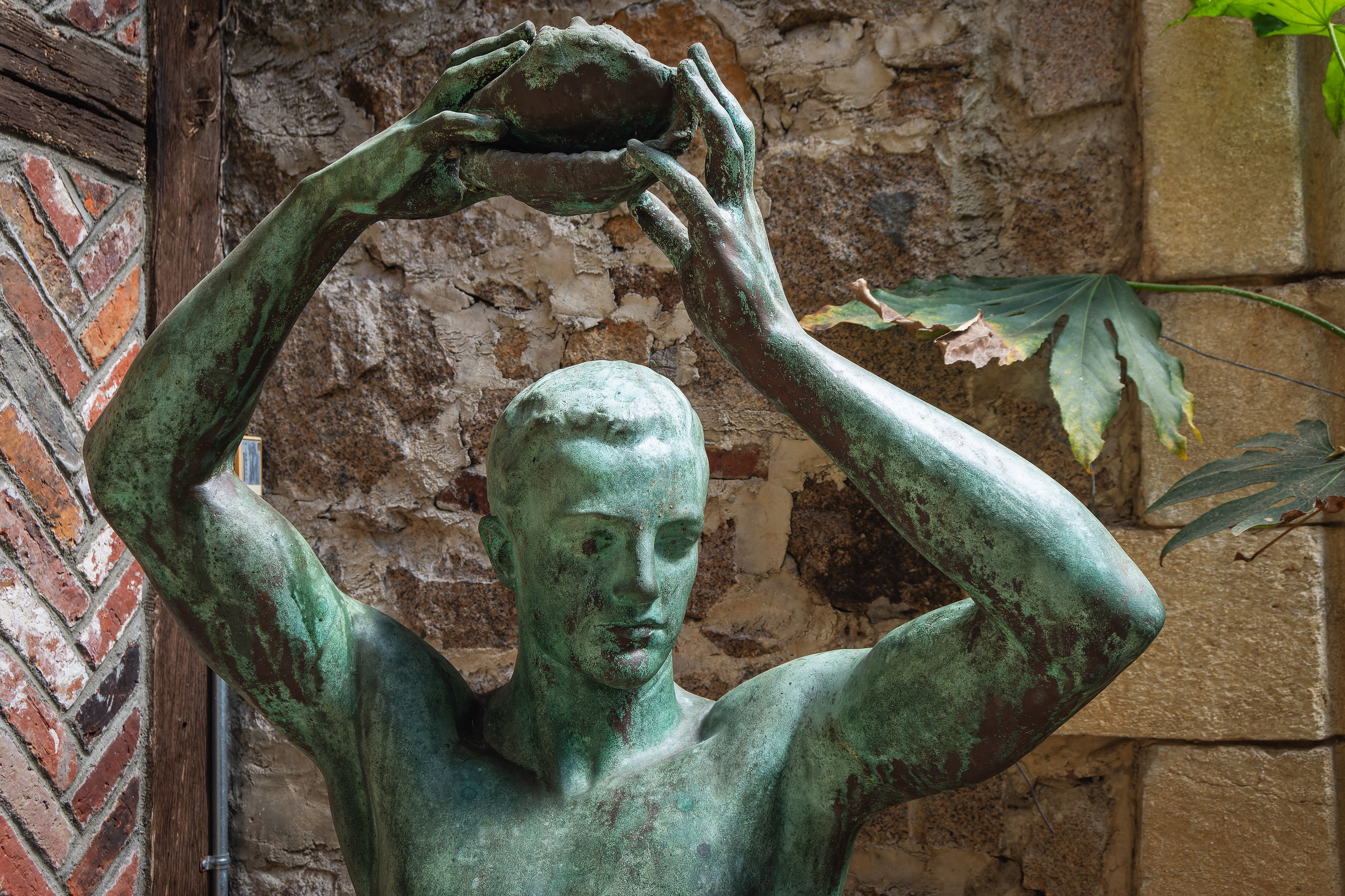 A bronze statue of a man holding a conch shell over his head