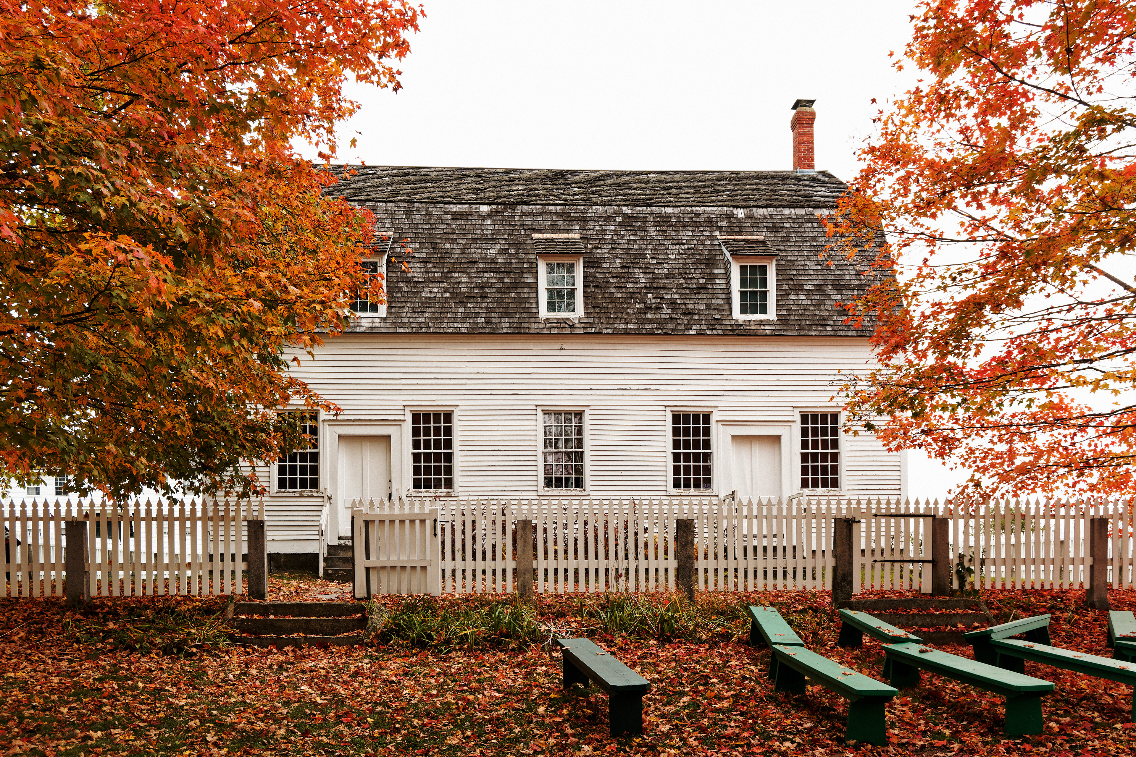 The meeting house sits in a field of fallen leaves.