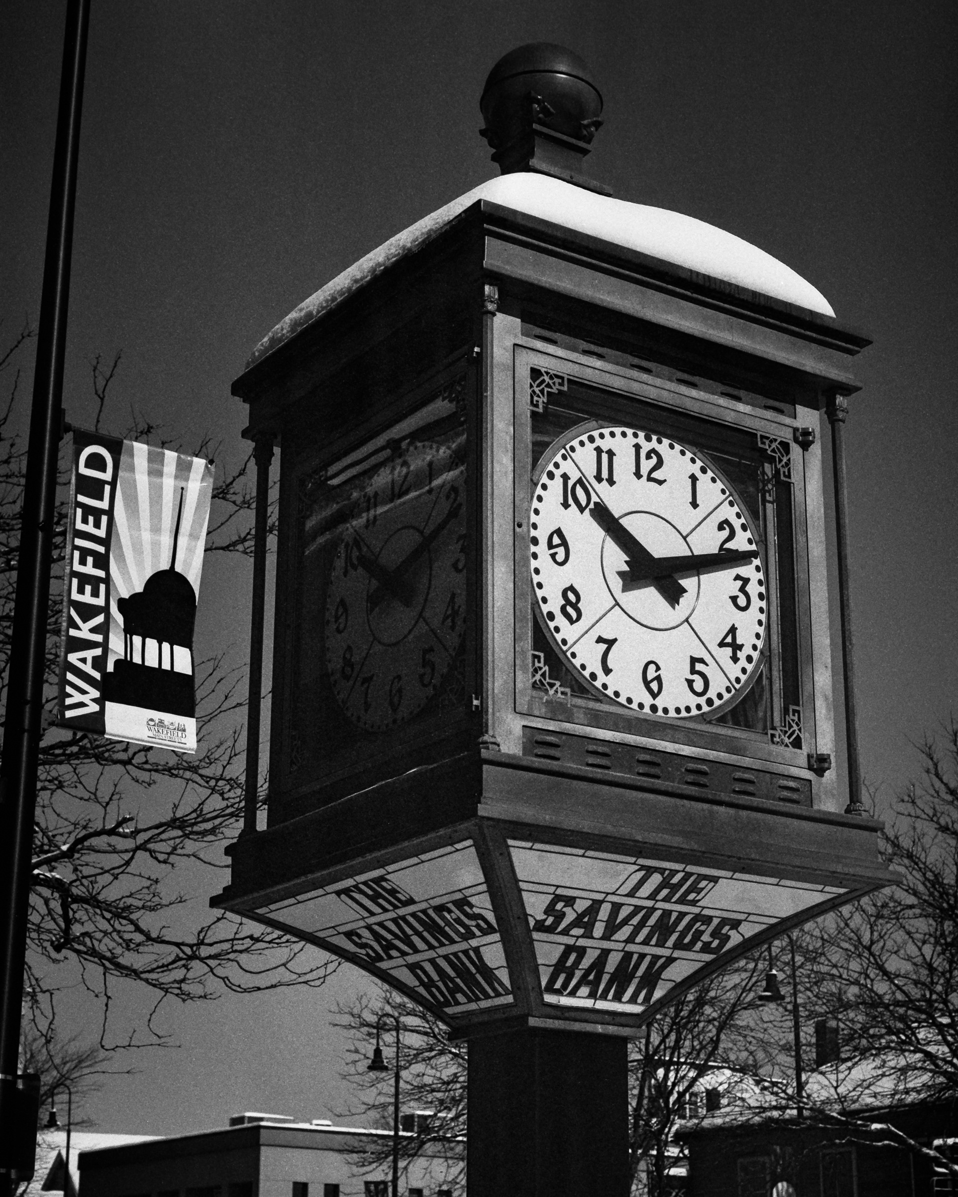 A vintage clock tower stands in the center of town after a snow storm.