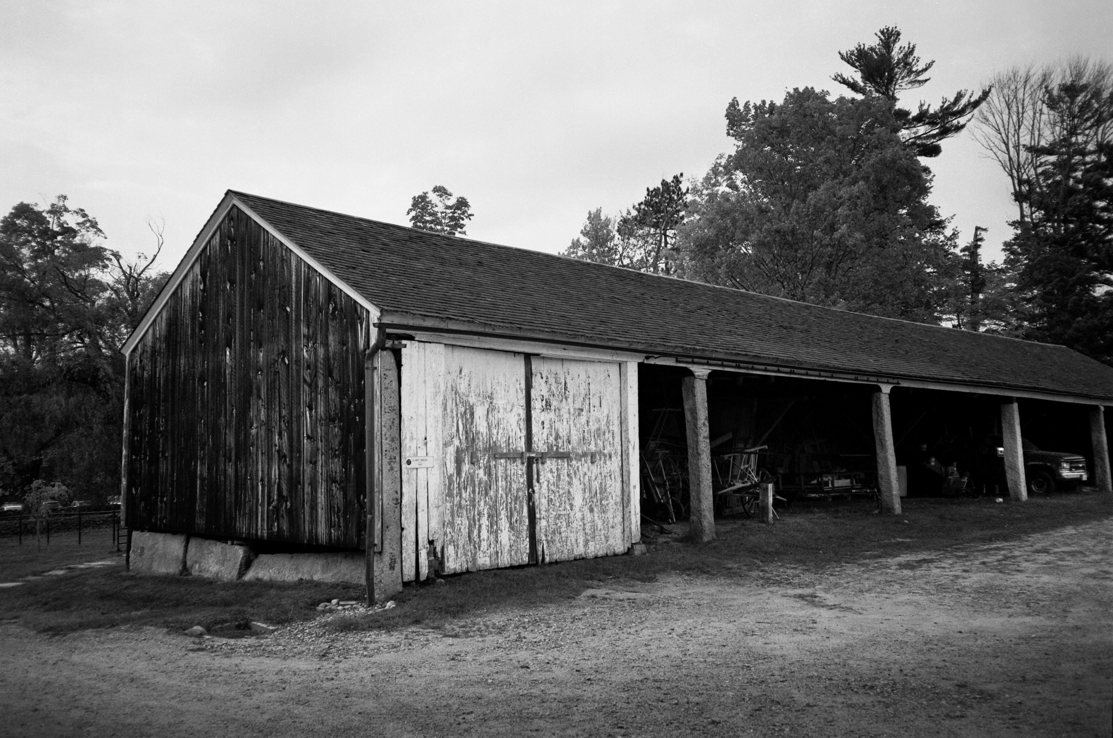 A vintage carriage house filled with farm equipment and a truck