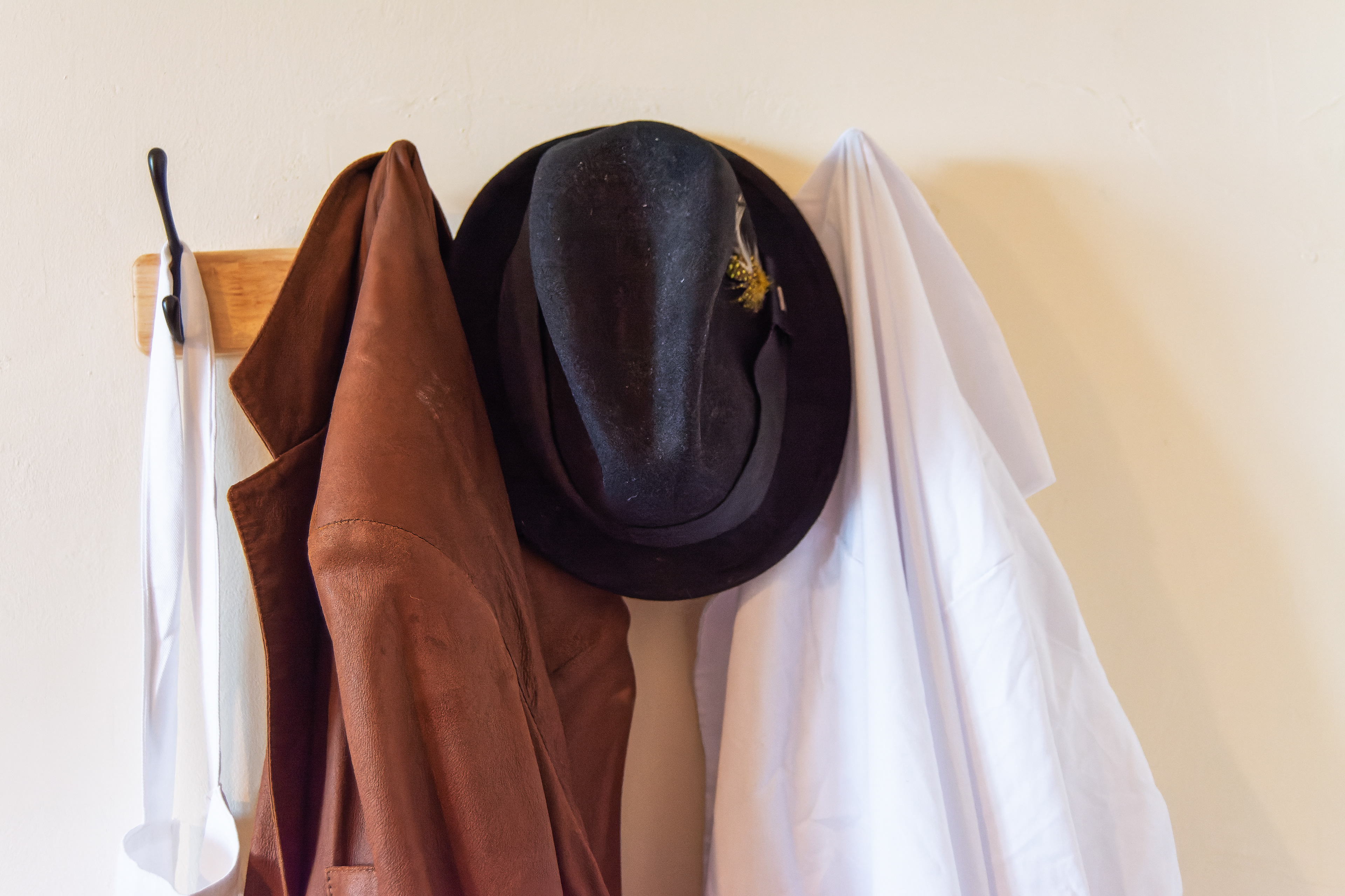 Apron, coats, and hat hang on wall