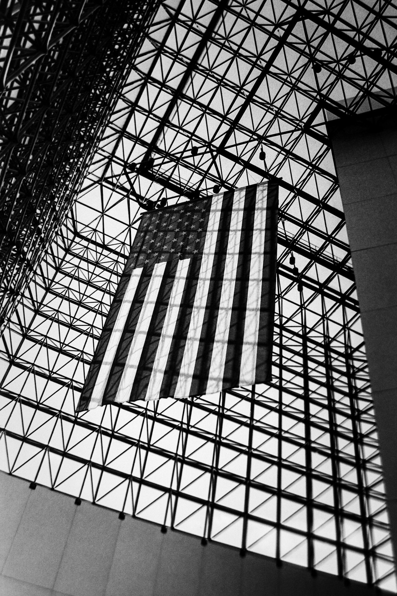 A massive American flag hangs from the ceiling of the beautiful glass pavilion of the John F. Kennedy Presidential Library in Boston, Massachusetts.