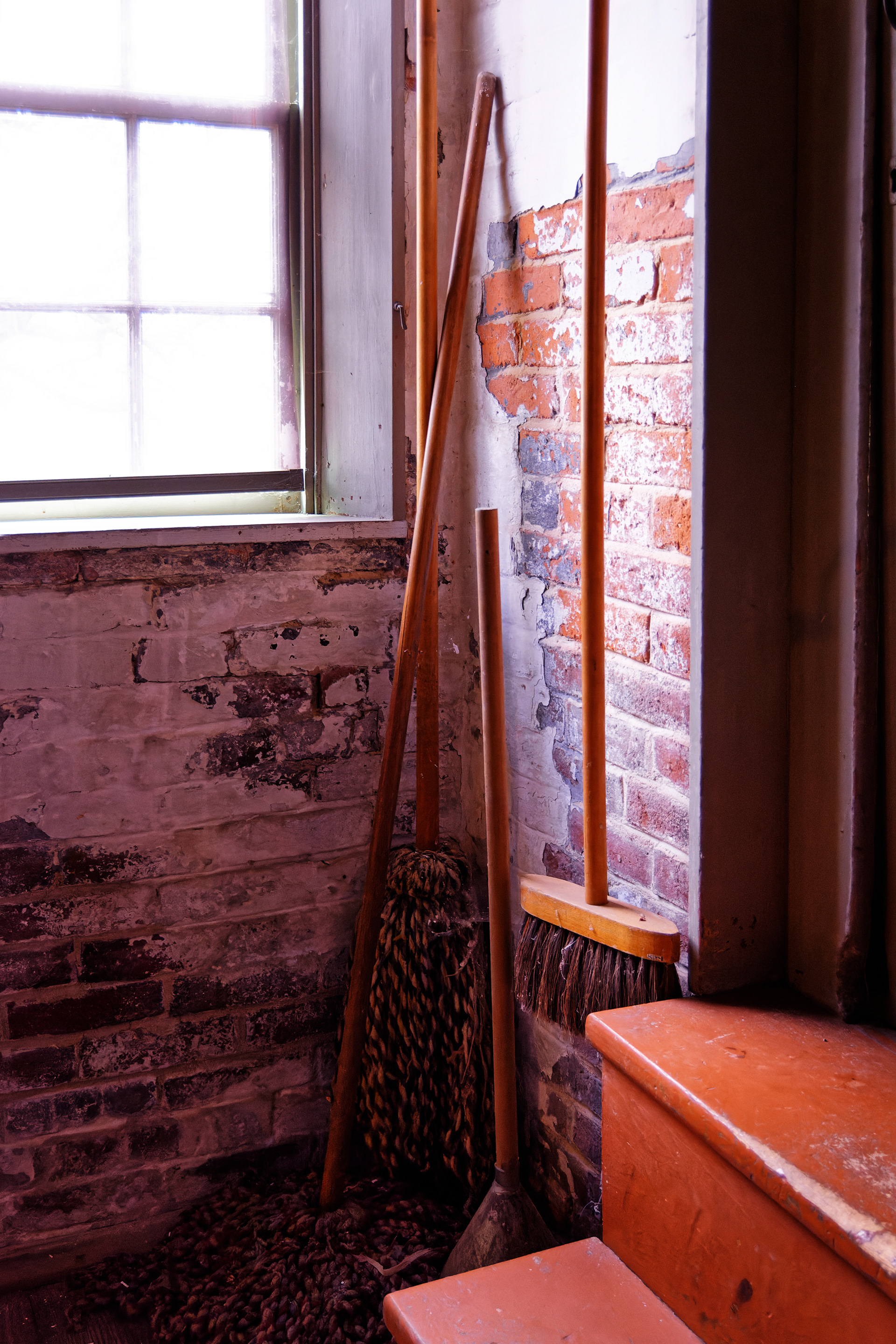 Mops and a broom hand from the wall in a corner of the laundry
