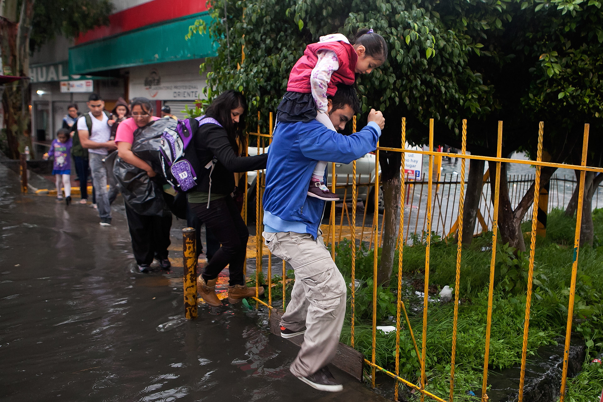 Personas intentan cruzar por una banqueta inundada en Iztapalapa, Ciudad de México. (Foto: Prometeo Lucero)