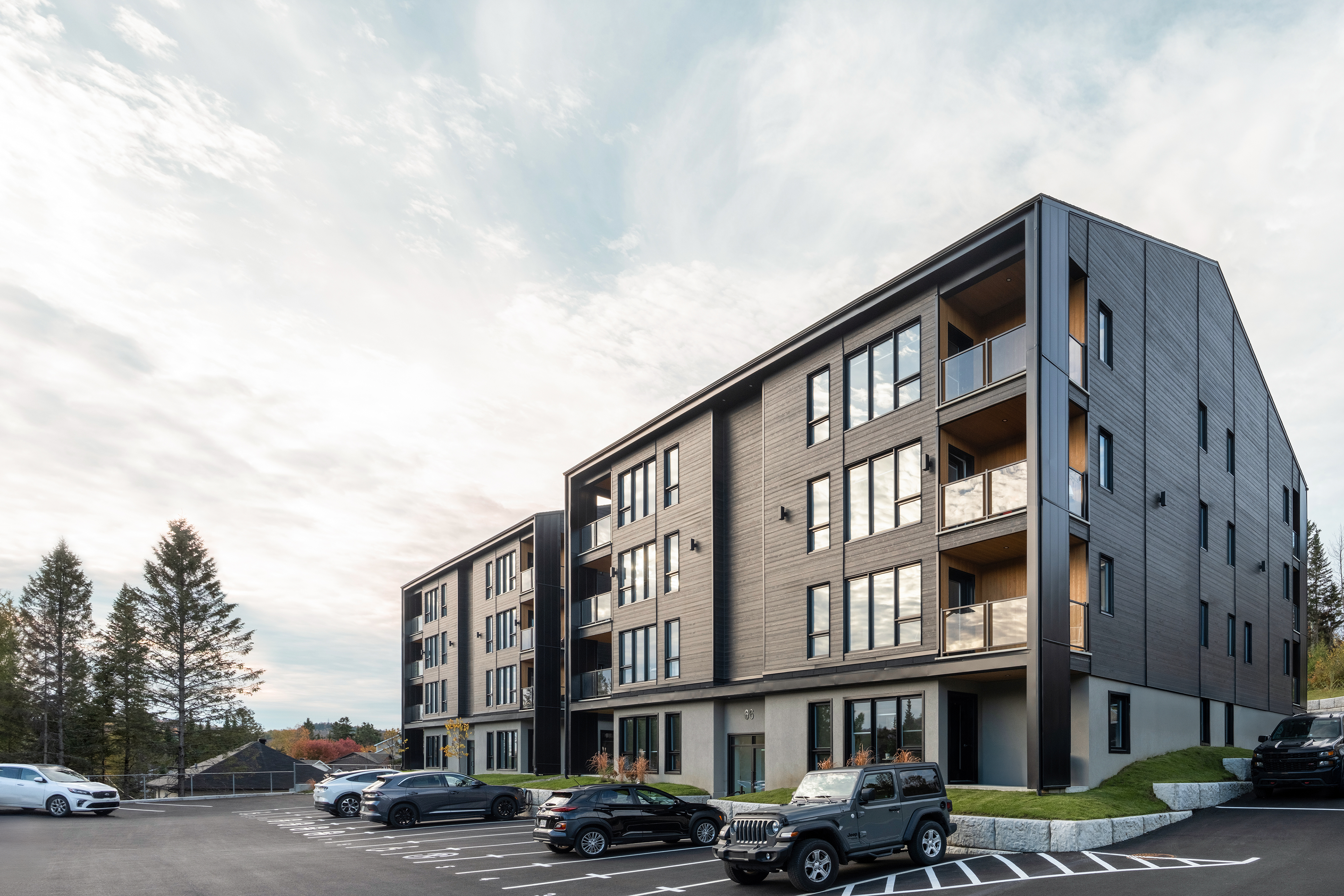 Condo en toile noir éclairé par un soleil levant, vus 3/4, grand ciel bleu tapissé de nuage légeré