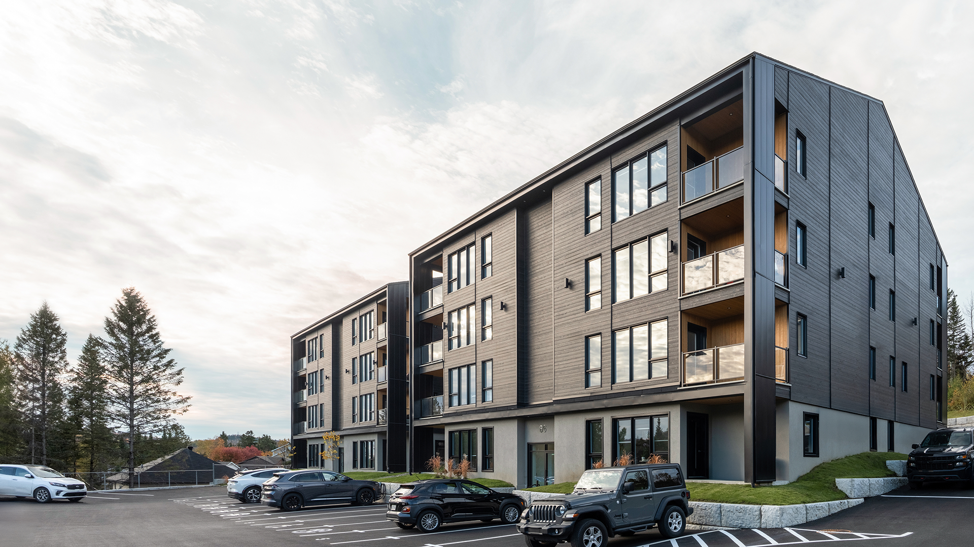 Condo en tole noir éclairé par un soleil levant, vus 3/4, grand ciel bleu tapissé de nuage léger