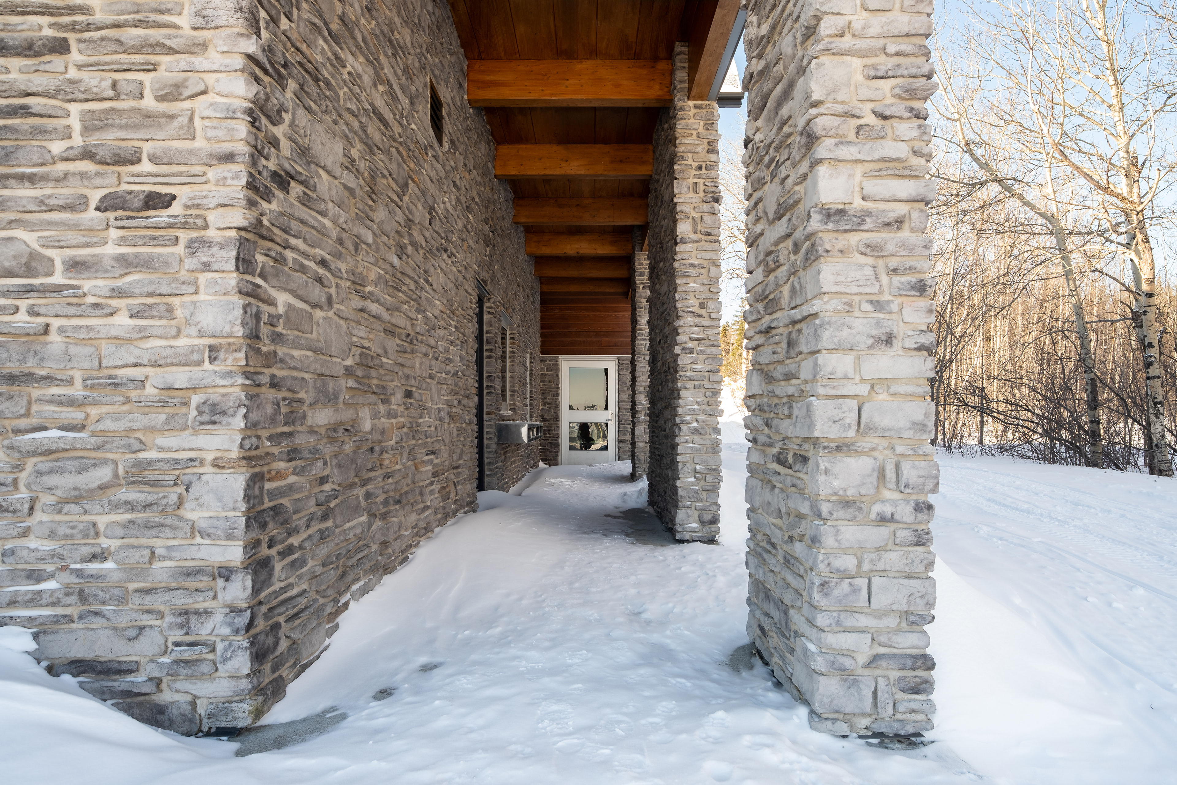 Passage extérieur en pierre et bois au Pavillon Mellon à Jonquière
