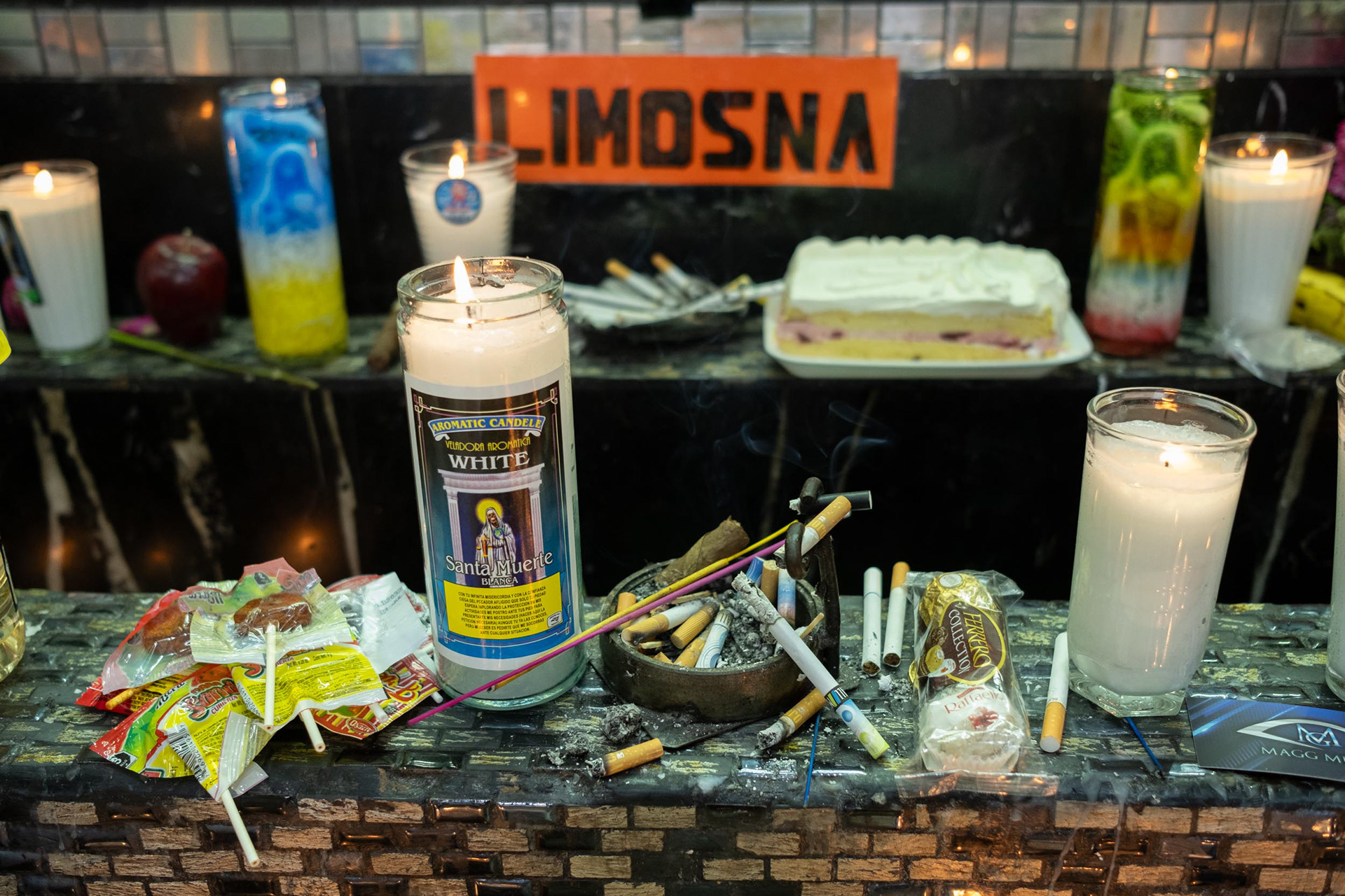Offerings of snacks, alcohol, cigarettes, flowers, and candles at the altar of Santa Muerte, also known as the 'White Girl,' in Tepito, Mexico City.