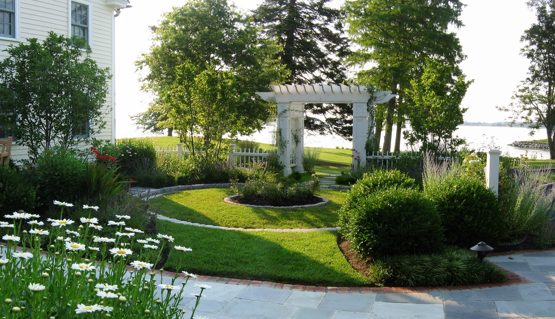 The circular garden is part of the entry garden to the main house as well as an arbored gateway to the beach.  The low picket fencing, perennials and small flowering trees create a sense of enclosure for the client and their guests, encouraging them to linger and meditate.