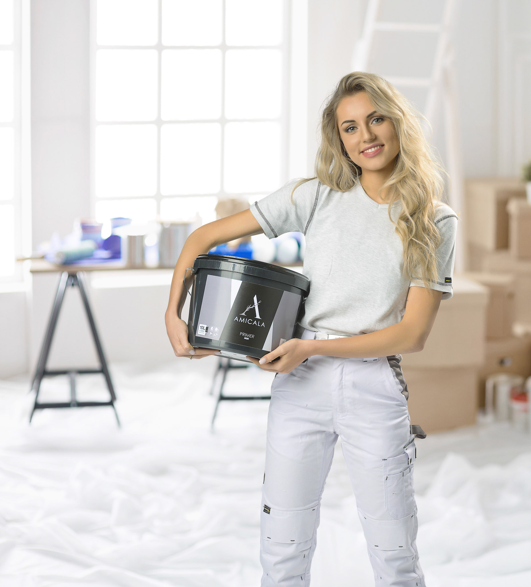Young woman moving house to new home holding cardboard boxes .
