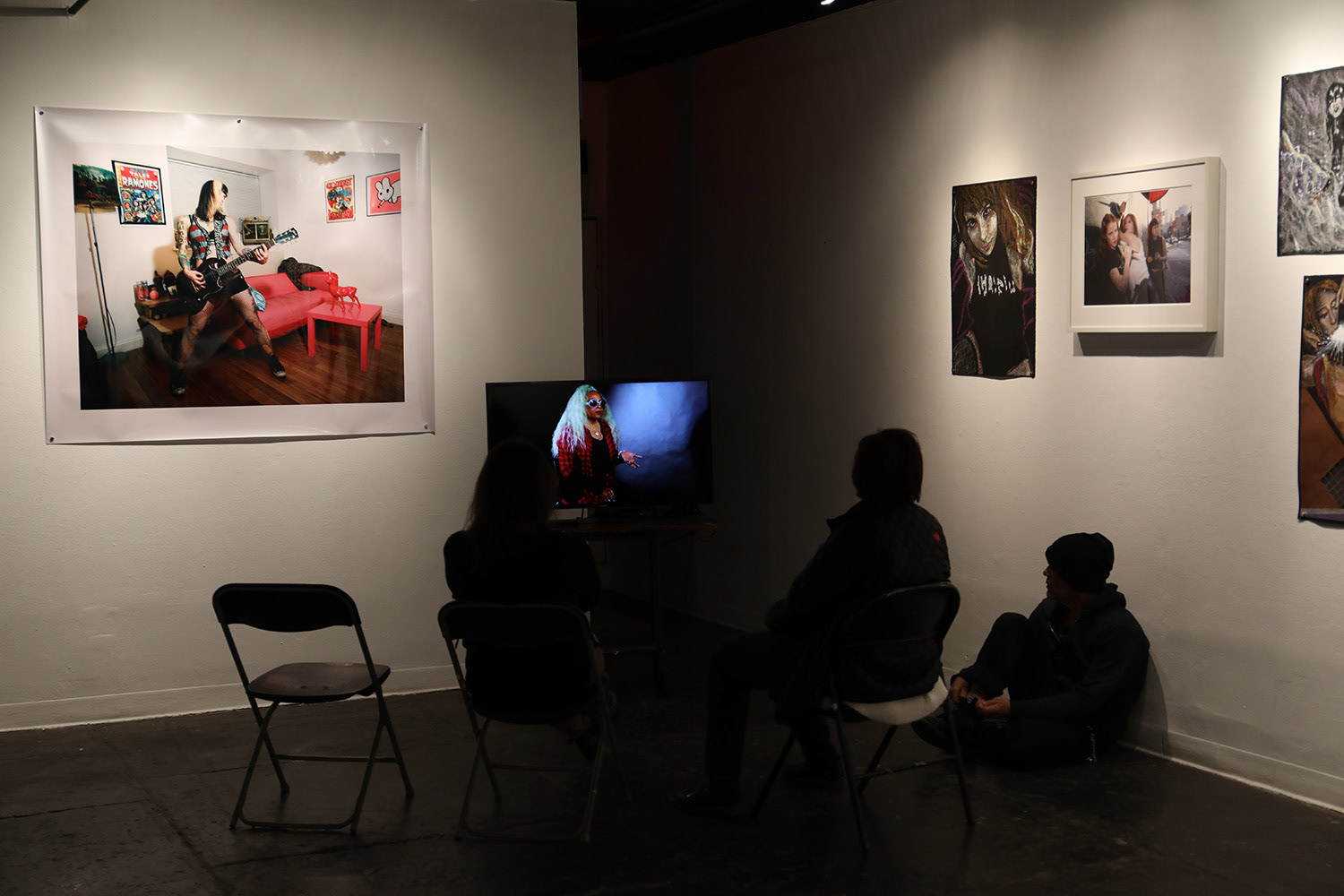 L-R Suzy Hotrod in her living room, Brooklyn (print on wall) Filmed Portrait Cid Scantlebury (on monitor) Feral Women Filmed Portraits Prince Street Project Space Leslie Lohman Museum NYC Katrina del Mar Immersive Exhibition