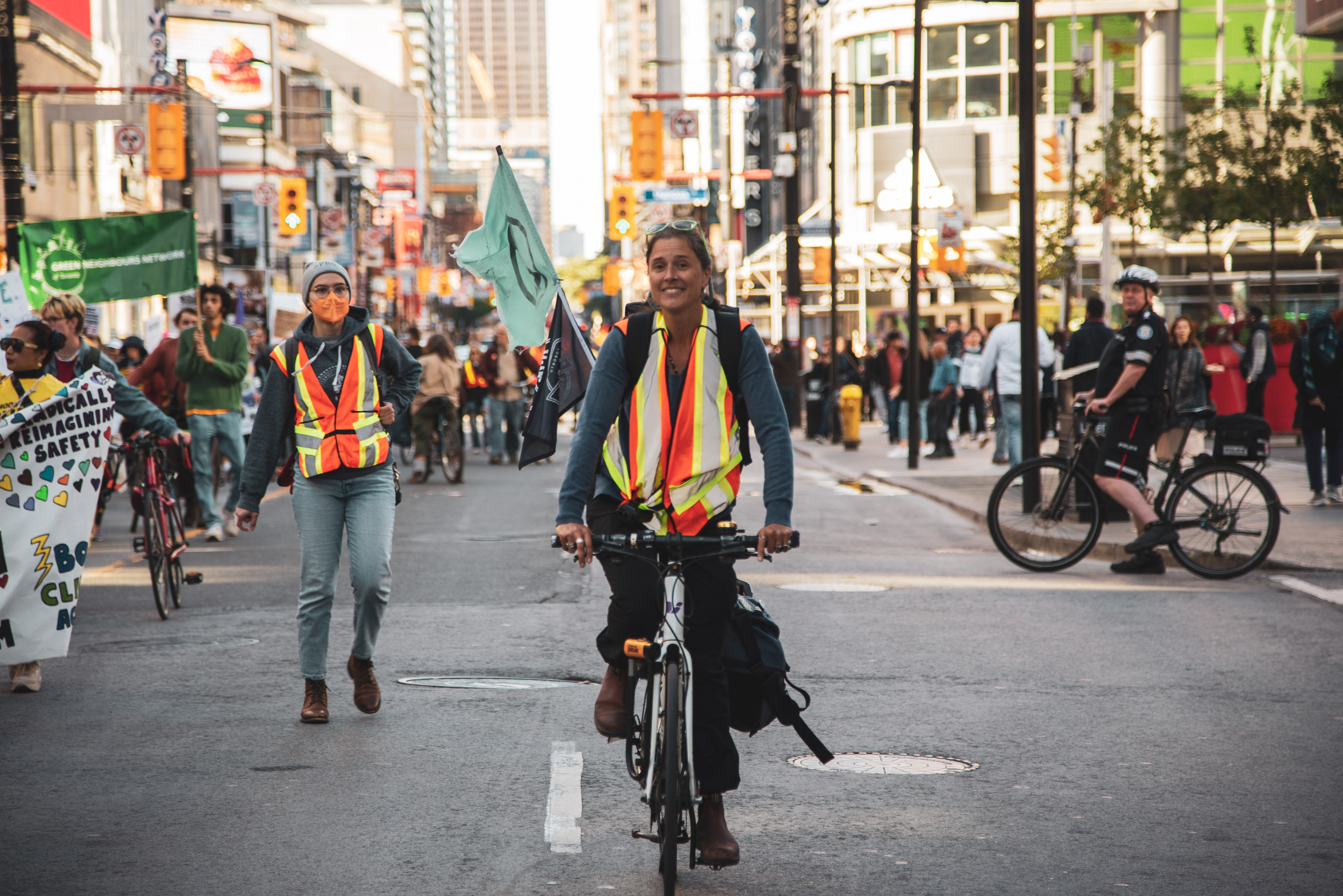 A volunteer protest marshall rides her bike as people march past Yonge and Dundas Square.