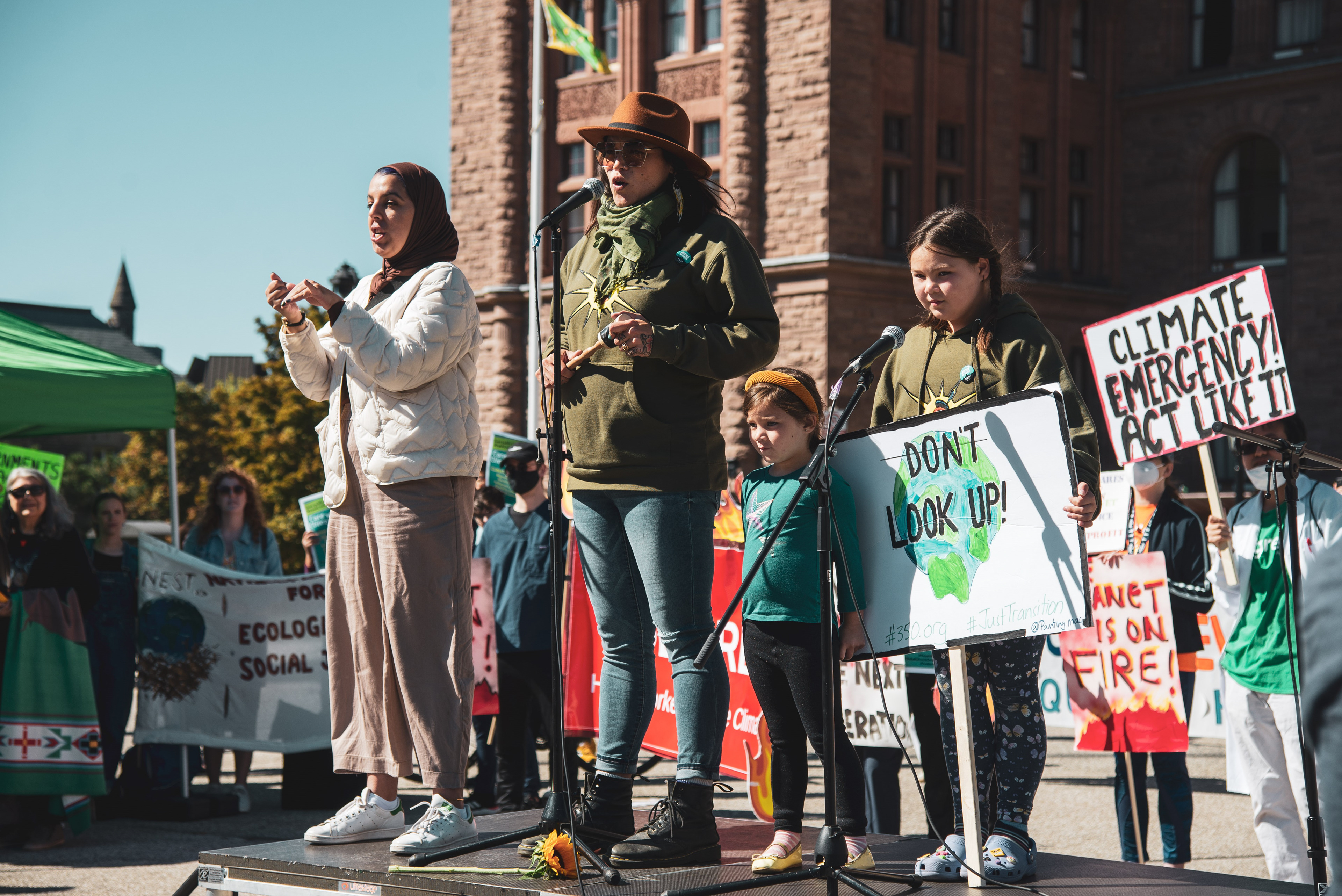 Vanessa Gray, a queer Anishinaabe Kwe and water protector from the Aamjiwnaang First Nation, speaks at the rally outside Queen's Park while an interpreter translates in ASL.