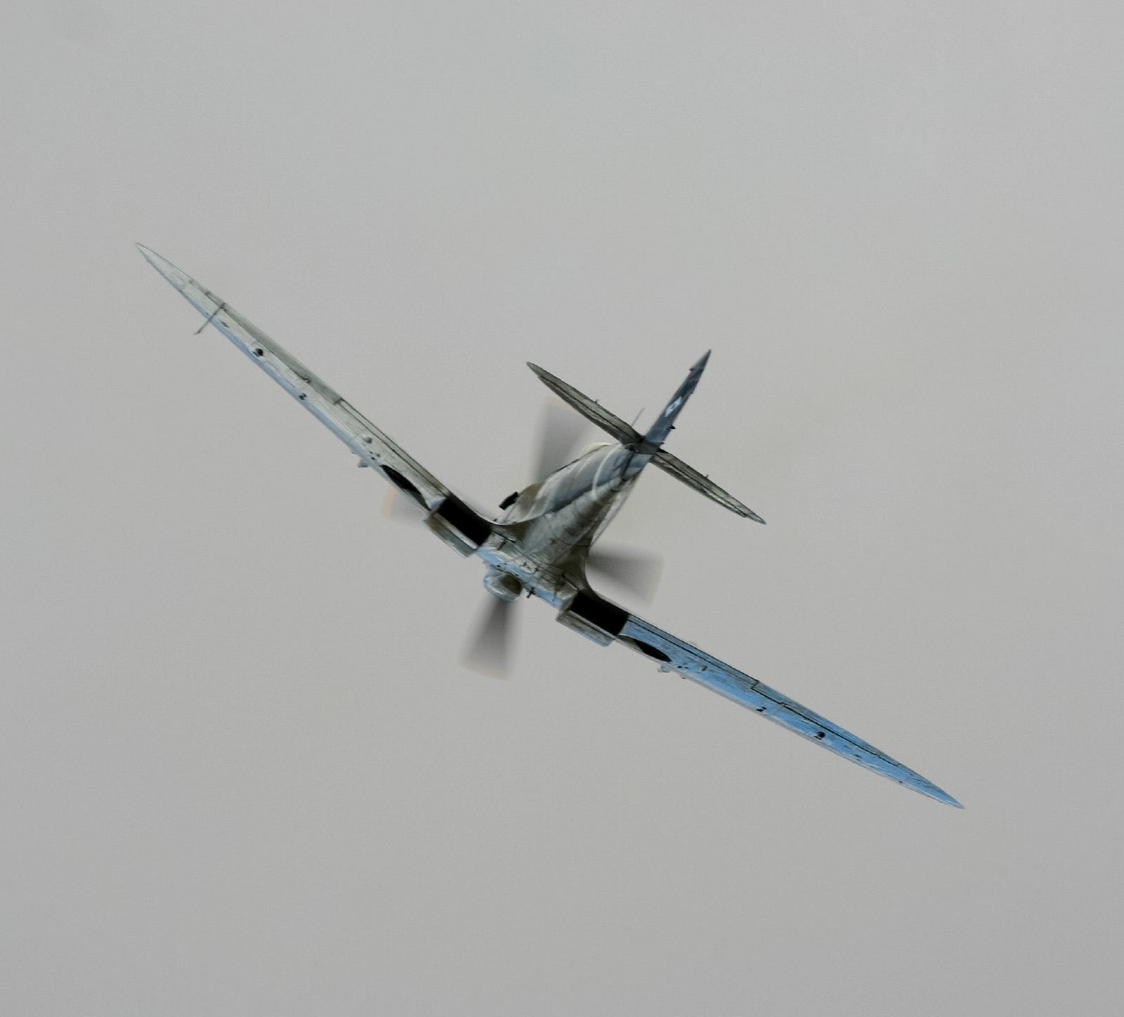 A Supermarine Spitfire Mk. XVI, a British single-seat fighter aircraft, flies through a featureless sky during an airshow event.