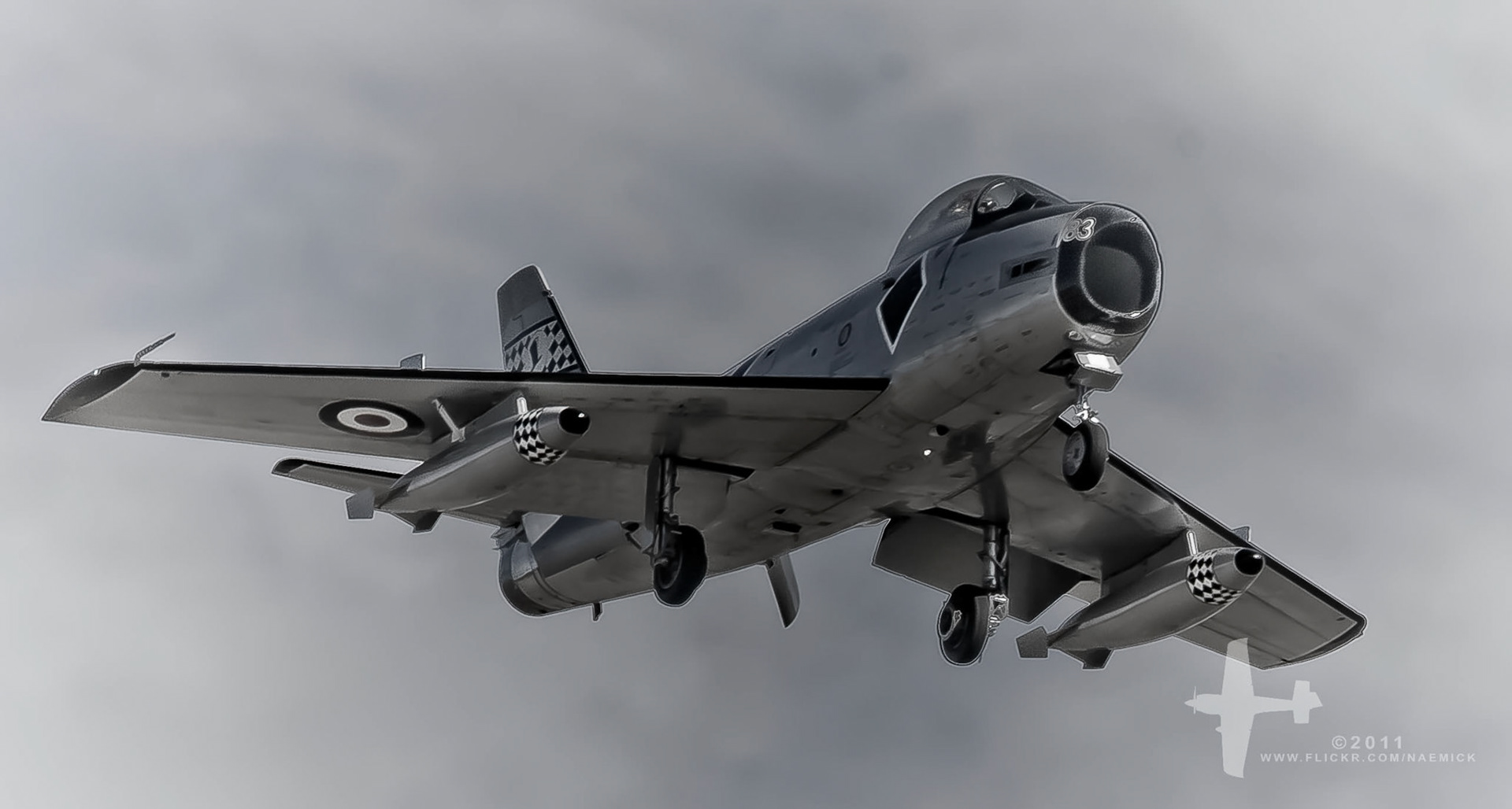 A Hawker Hunter F.6 jet aircraft, bearing the Royal Air Force roundel and code "183" on its nose, is captured mid-flight with its landing gear deployed.