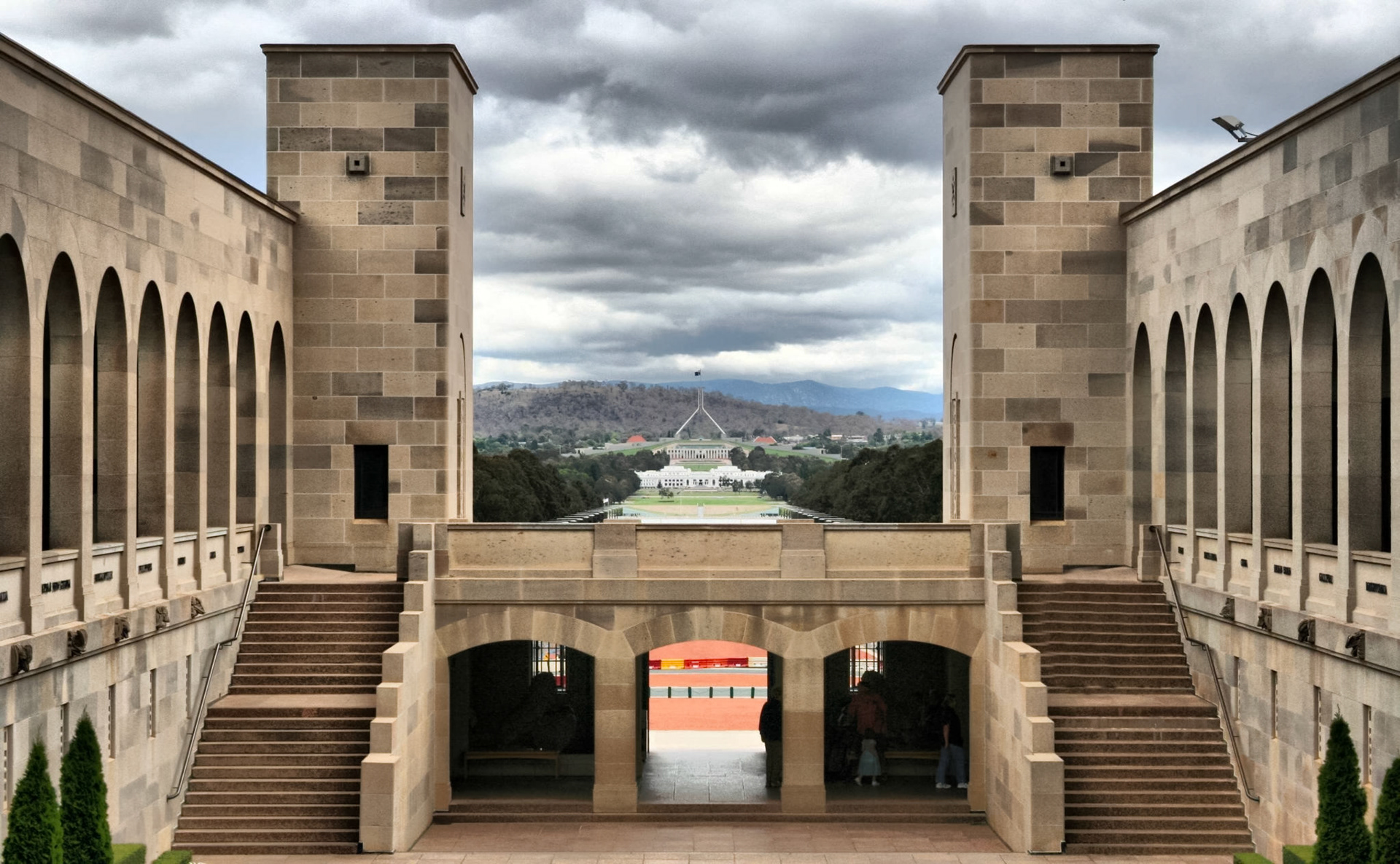 The Australian War Memorial in Canberra features architectural elements and a view towards Parliament House under a cloudy sky.