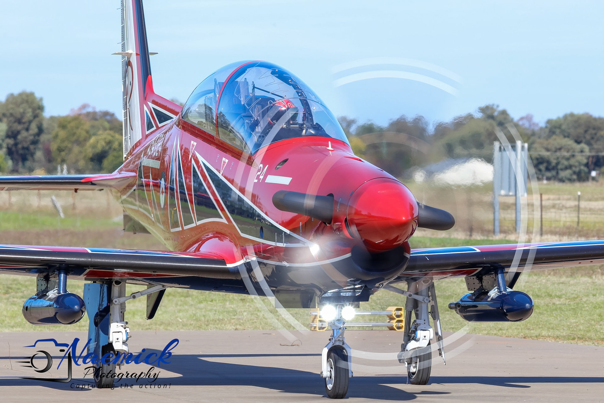 A red and black military training aircraft, Pilatus PC-21, with "24" on its side, is parked on the tarmac in Temora, New South Wales, Australia.