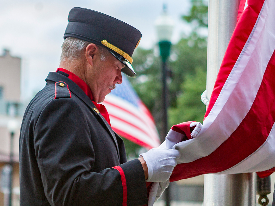 NBFD Honor Guard member Adam Kanz bows his head for a prayer before raising the flag in remembrence of 9/11 at the Main Plaza on Sep. 11, 2024. BLAINE YOUNG | Herald-Zeitung
