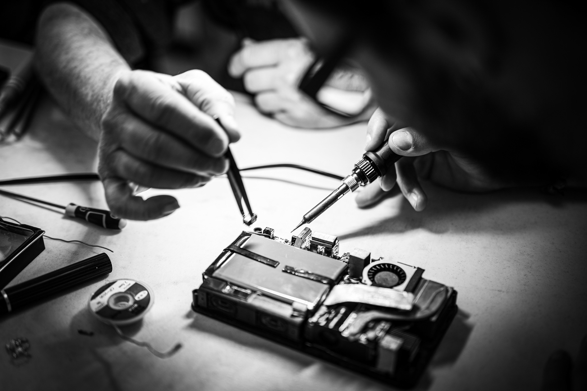 Réparation minutieuse à quatre mains sur un circuit électronique atelier participatif Repair Café, Montpellier