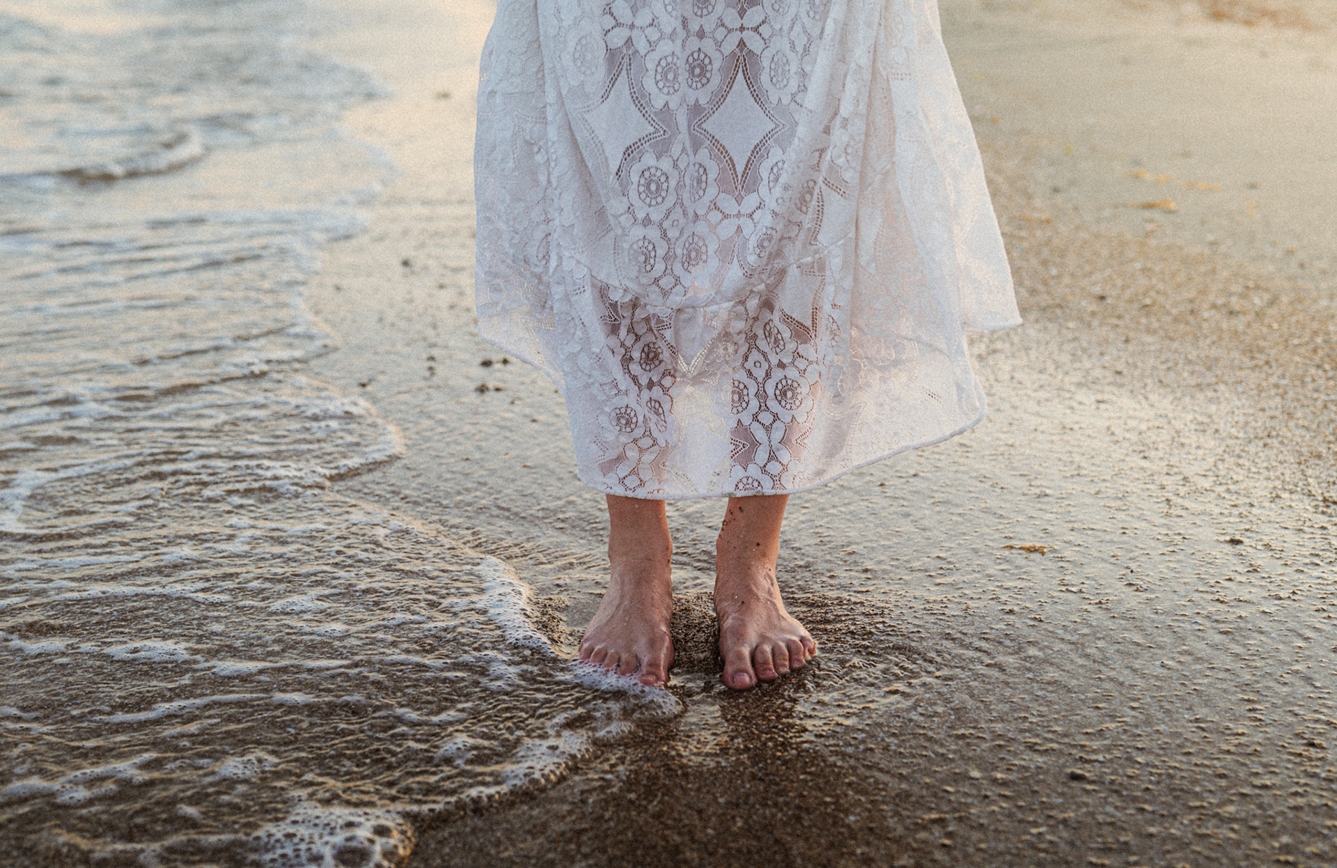 Robe en dentelle blanche mouillée par les vagues au coucher du soleil