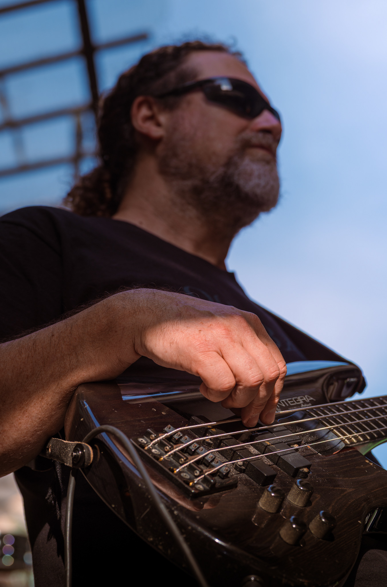 Plan serré sur le jeu du bassiste du groupe Outback pendant la Fête de la Musique