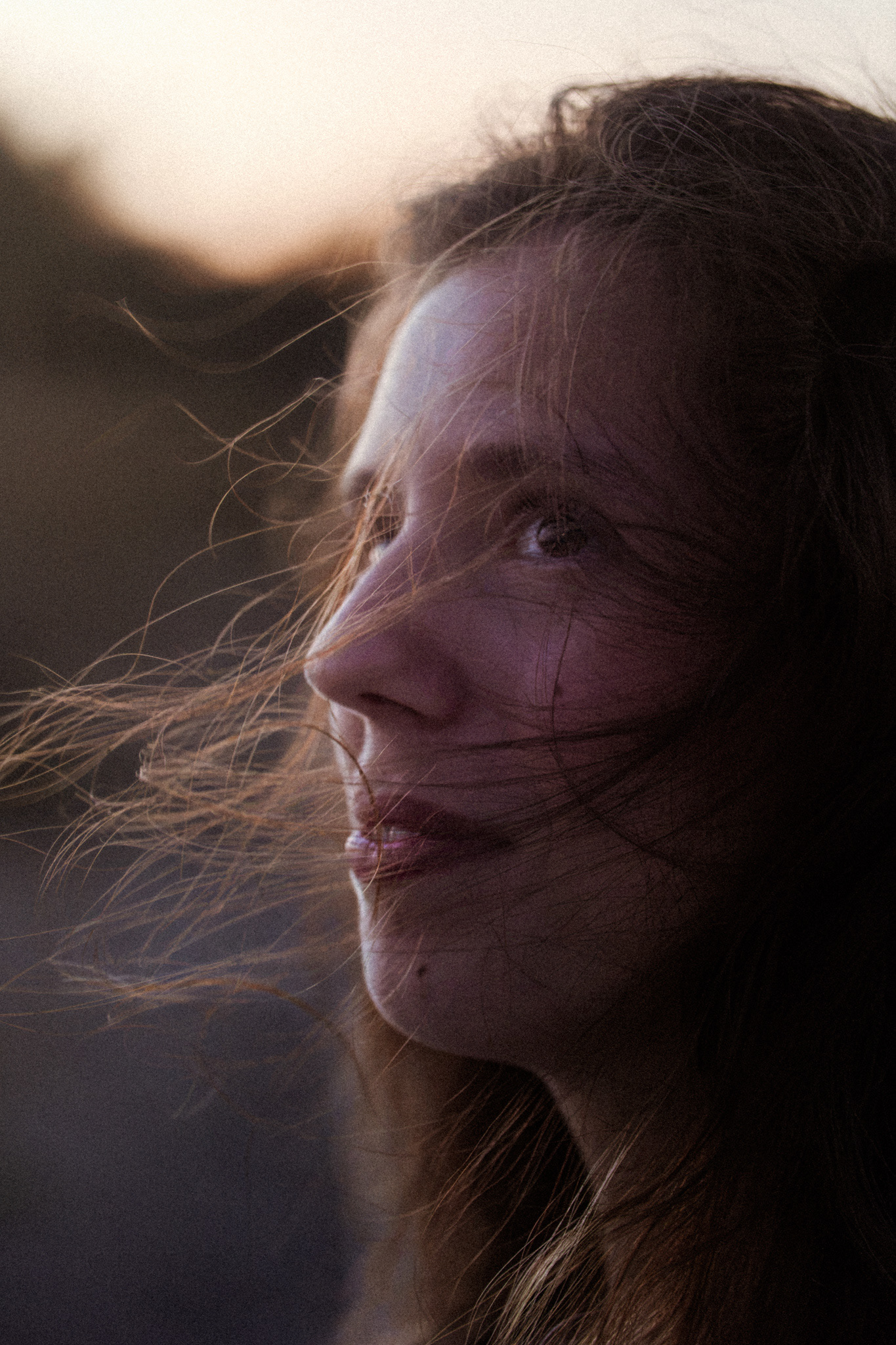Portrait serré d'Agathe, cheveux dans le vent au coucher du soleil