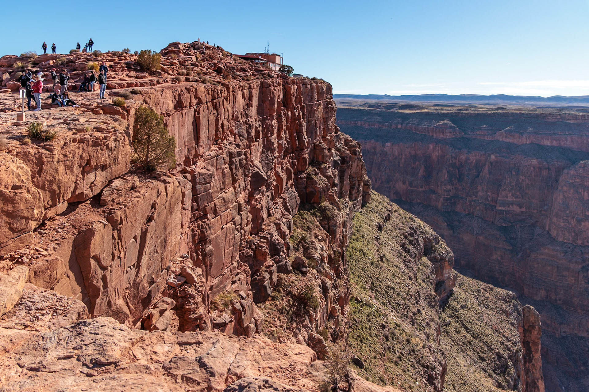 230405_258 Visitors climb on rock formation rising above the canyon at Guano Point in Grand Canyon West near Peach Springs, Arizona