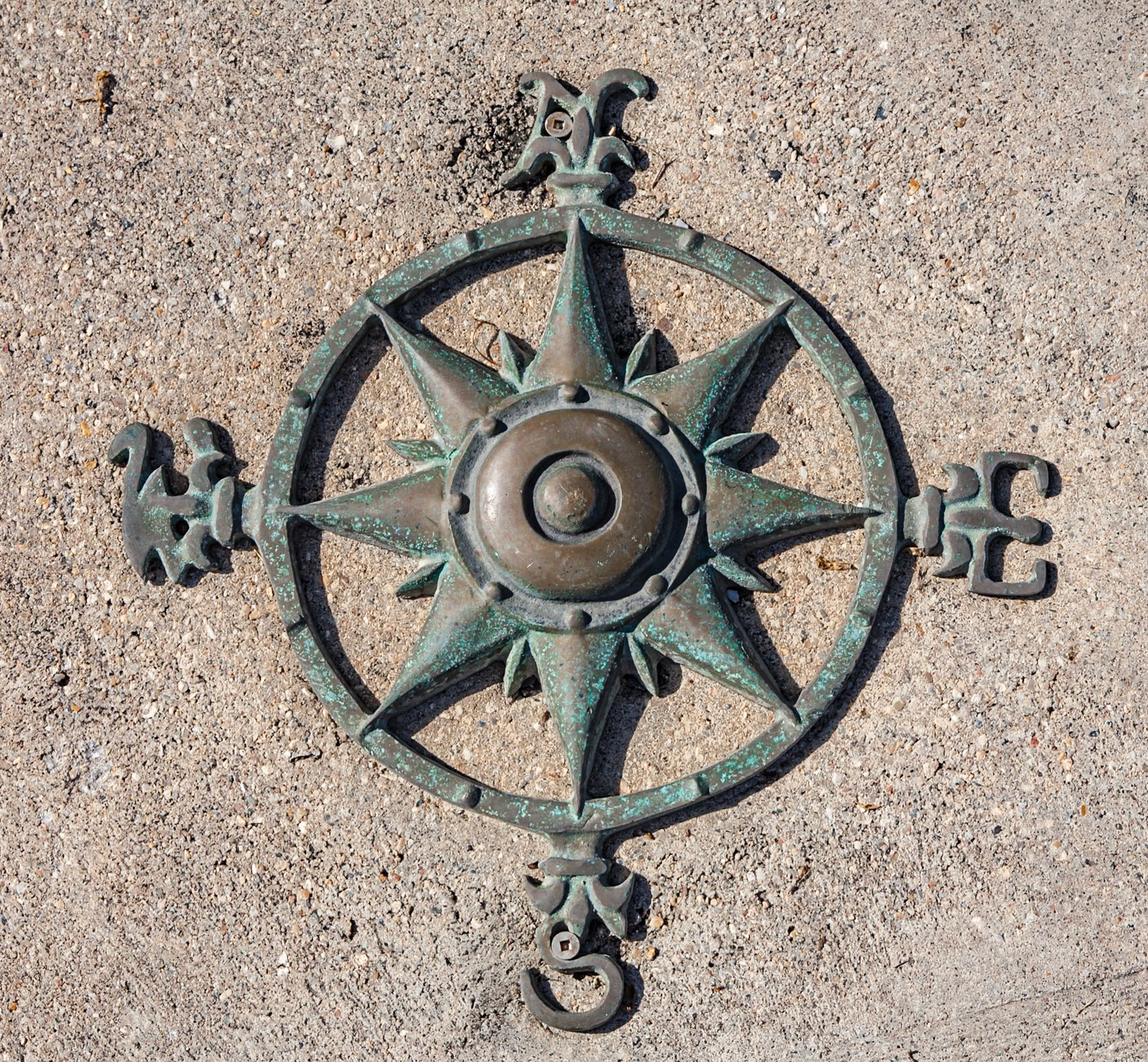 140617_556 Old wind rose navigational compass symbol attached to concrete sidewalk at the Pass Christian Yacht Club in Pass Christian, Mississippi